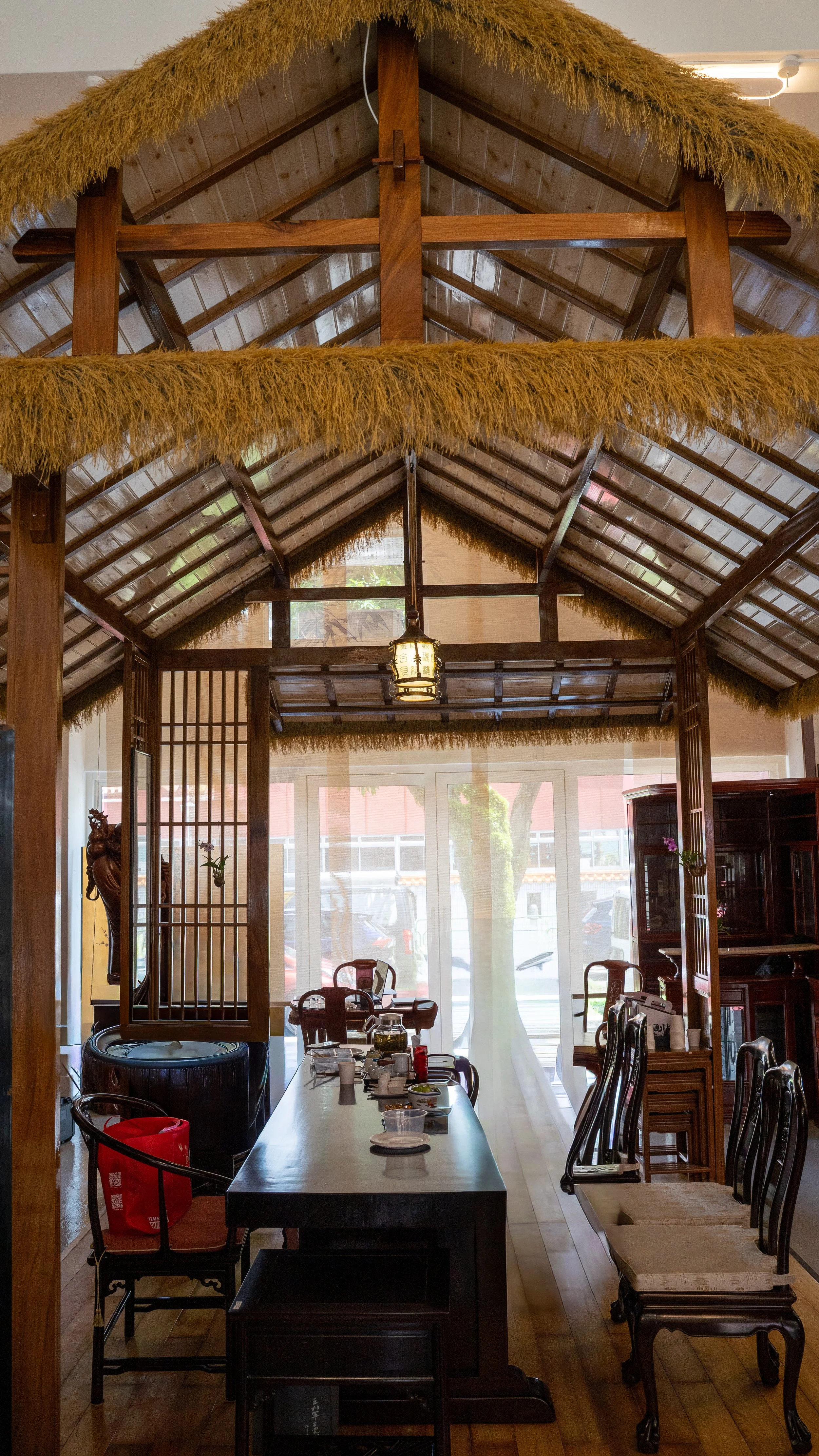 Interior of a traditional Asian-style restaurant with wooden furniture, a thatched roof, and decorative elements.