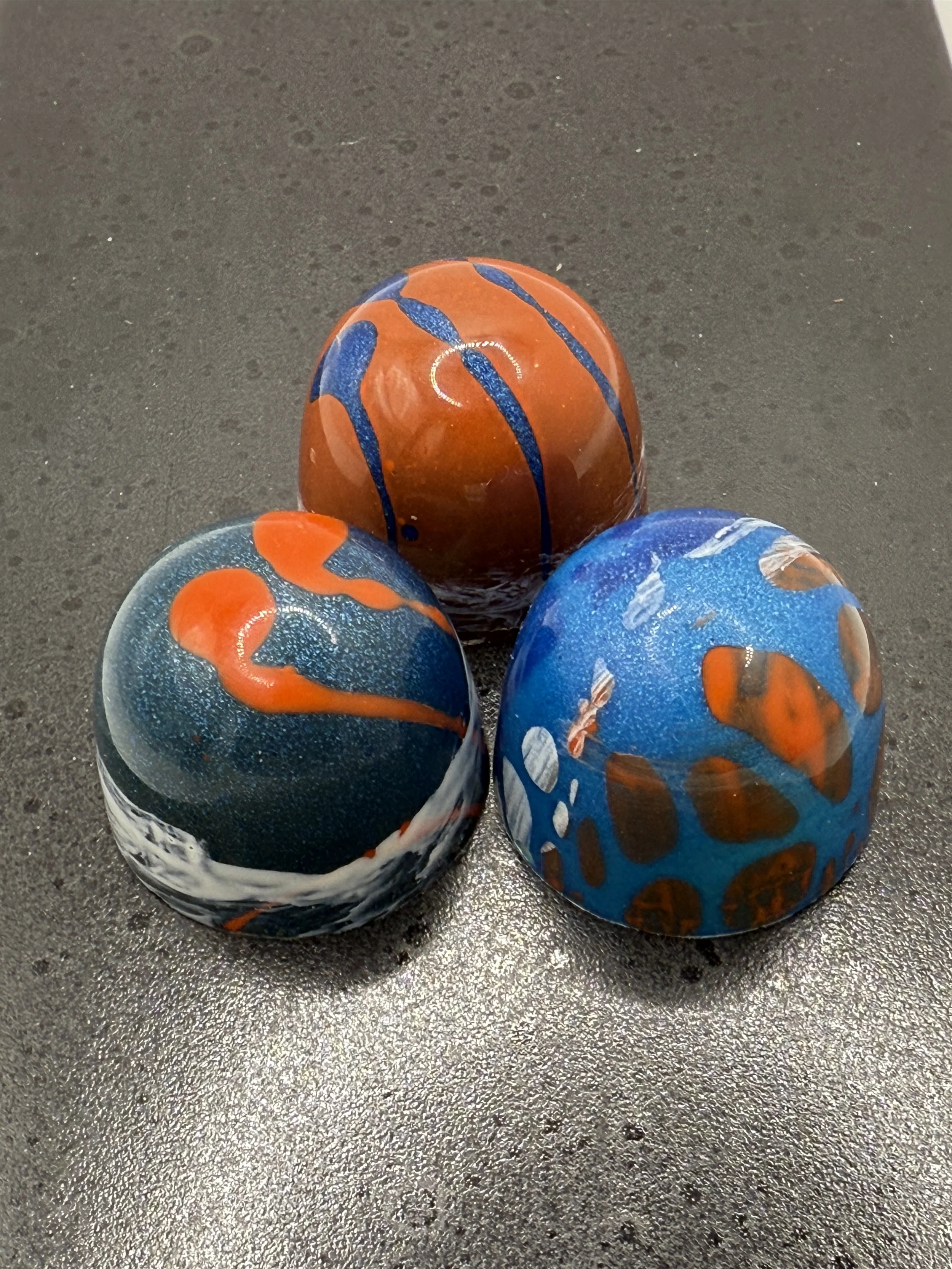 Three decorative artisan chocolates, hand painted with colorful abstract patterns