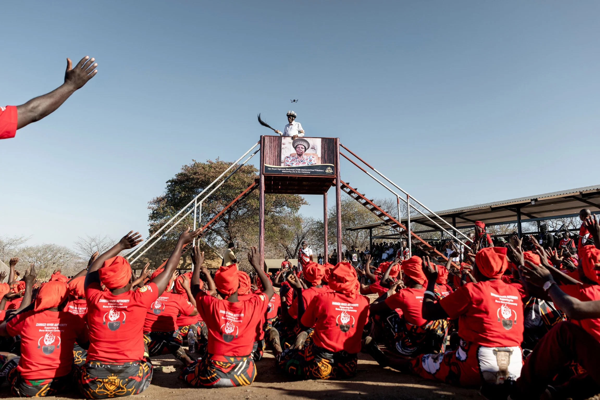 Point culminant de la cérémonie du Bene Mukuni : des femmes en tenue rouge accompagnent la montée symbolique des marches du Chef Mukuni, geste rituel retraçant l'histoire et le parcours historique de la communauté Toka Leya. Zambie, Simukale - 26 Jui