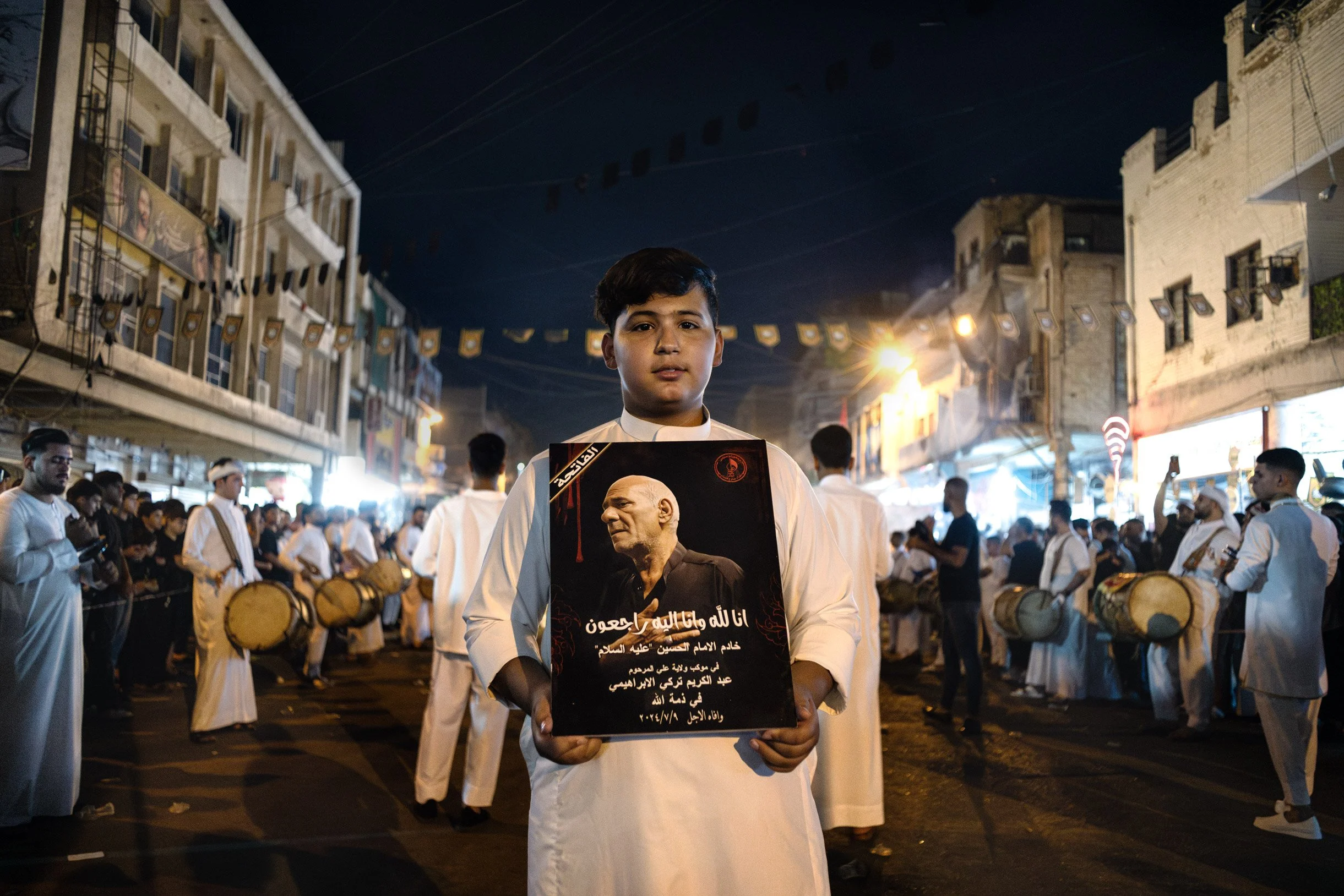 Les fidèles commémorent le martyre de l’imam Hussein à travers des rituels de deuil. Au milieu des différentes processions pendant le 8ème jour de la commémoration de Achoura, un enfant tient le portrait d’un défunt de sa famille. Baghdad, Iraq, Juil