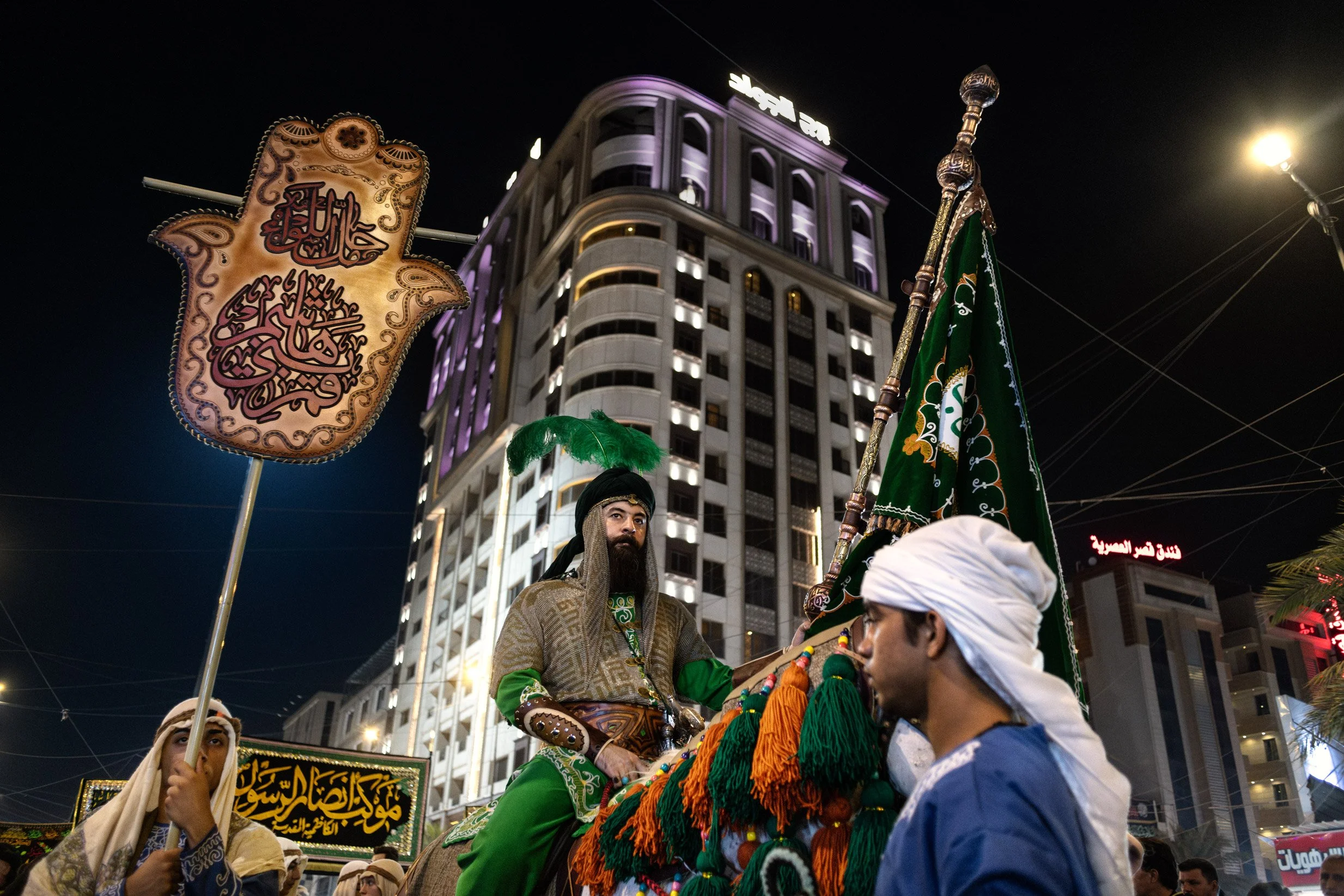 Les fidèles commémorent le martyre de l’imam Hussein à travers des rituels de deuil. Un homme se tient fièrement sur un cheval, en habit traditionnel, représentant l'histoire d'Hussein lors du 7ème jour de Achoura. Baghdad, Iraq, Juillet 2024. 