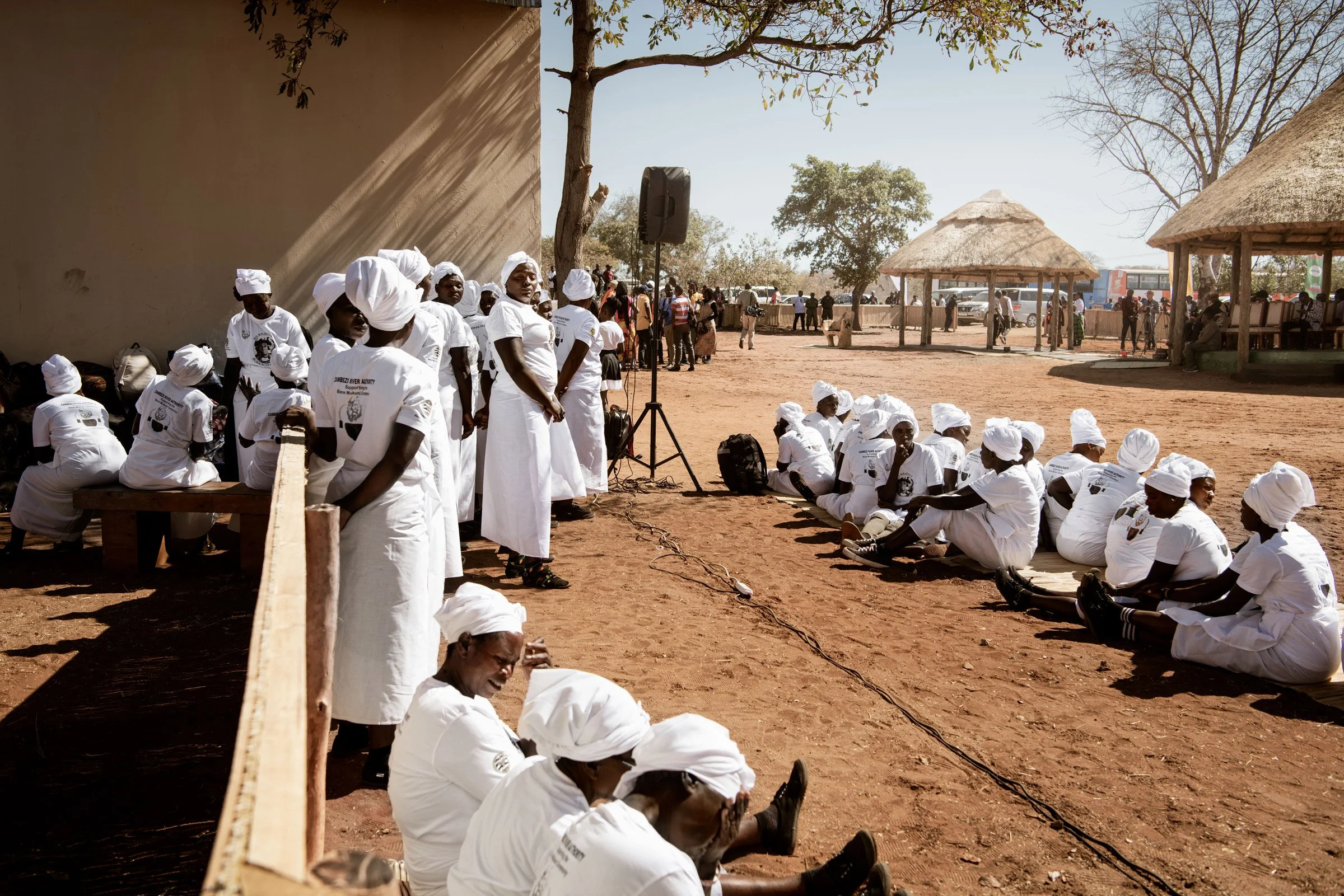 Les femmes Toka Leya, vêtues de blanc et assises en groupe, attendent le commencement des rituels et danses traditionnelles en l'honneur du Chef Mukuni lors du dernier jour de la cérémonie du Bene Mukuni. Zambie, Simukale - 26 Juillet 2025