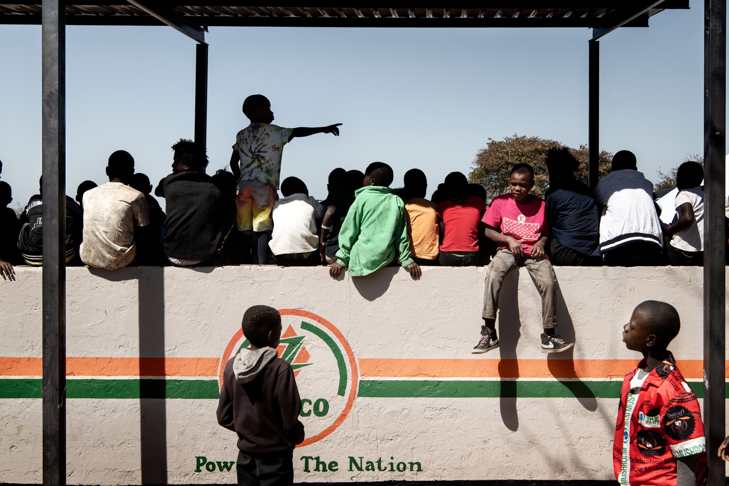 Des enfants spectateurs du dernier jour de la cérémonie du Bene Mukuni observent les festivités depuis les gradins construit et décorés pour l’occasion. Zambie, Simukale - 26 Juillet 202