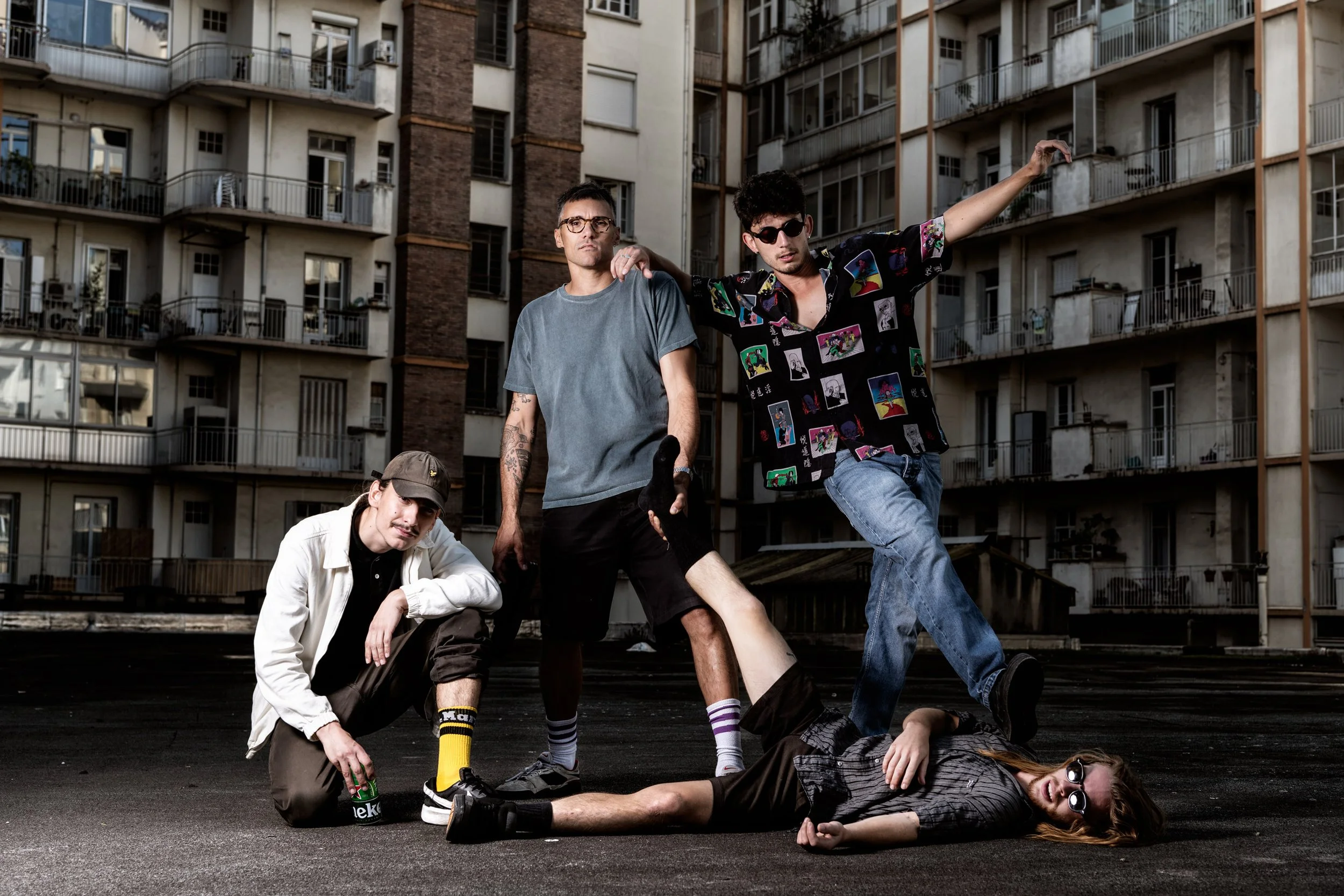 Un groupe de cinq jeunes adultes dans une scène urbaine, avec un immeuble multicolore en arrière-plan.