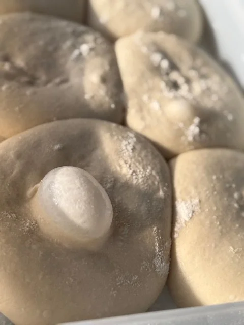 Close-up of raw dumplings with a doughy exterior, some dusted with flour.