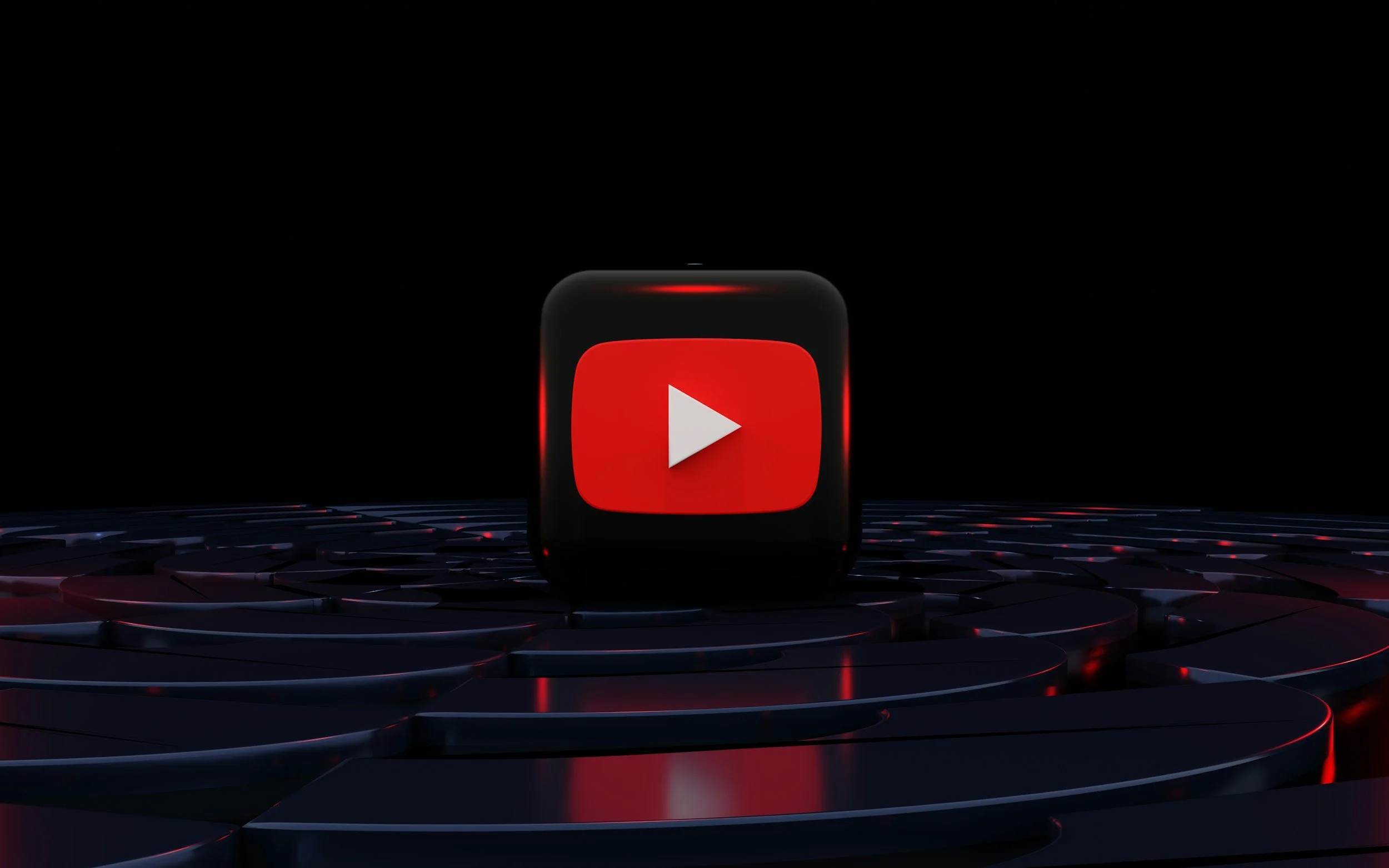 A digital 3D-rendered icon of the YouTube logo on a small black cube, displayed on a dark, reflective surface with a black background.