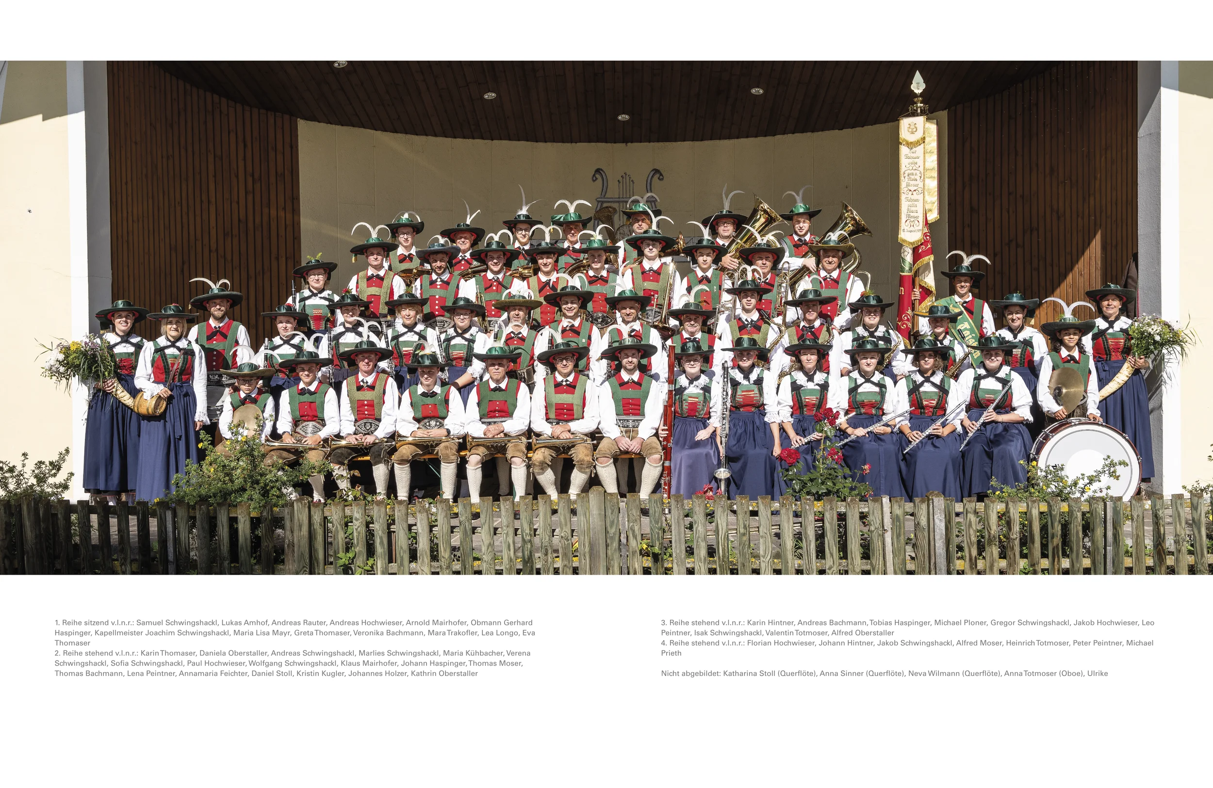 Gruppe von Menschen in traditionellen Trachten mitその Instrumenten auf einer Bühne, vermutlich bei einer kulturellen Veranstaltung in Deutschland.