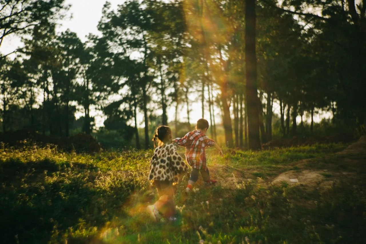 Two children running through a sunlit forest during the golden hour, capturing the spirit of adventure and play.