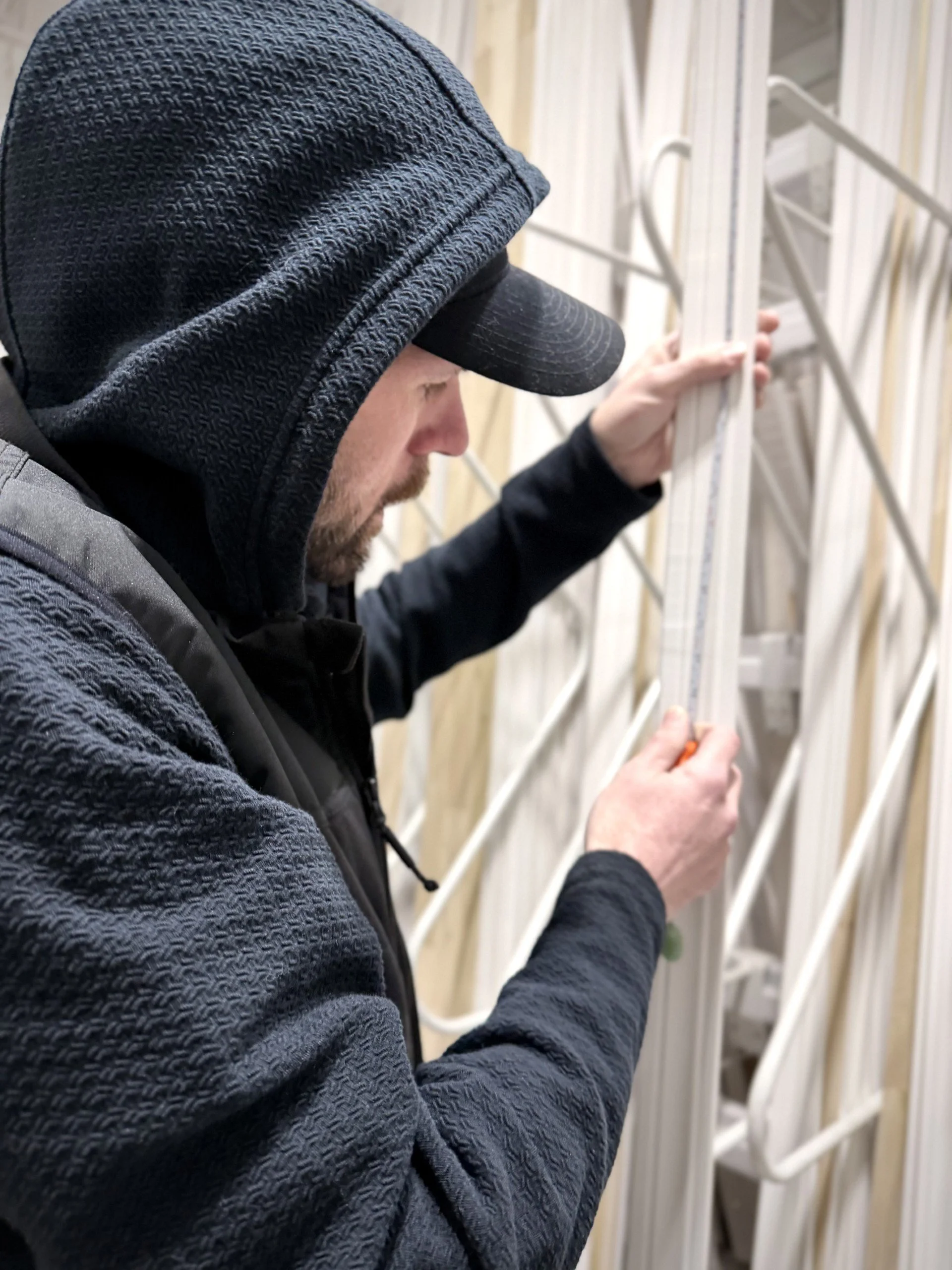 Window and door installer measuring for custom trim installation during a home repair project in Dundas, Minnesota.