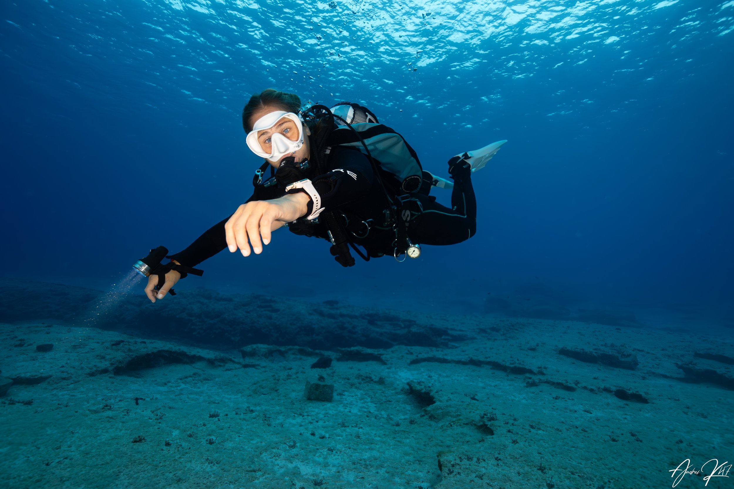 Scuba diver exploring the seabed at night with torch light during a guided night dive in Cyprus.