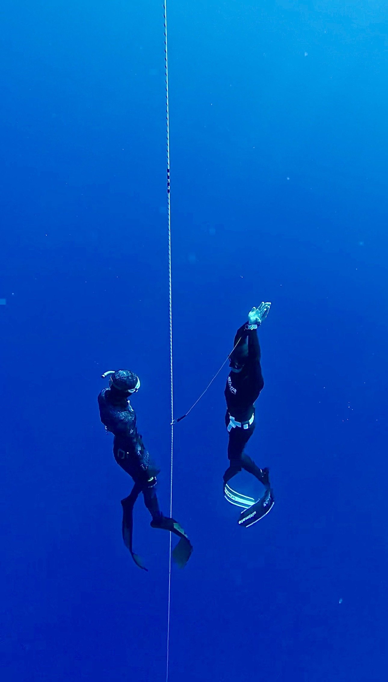 Two freedivers practicing safety procedures along a training line in deep blue water in Protaras, Cyprus