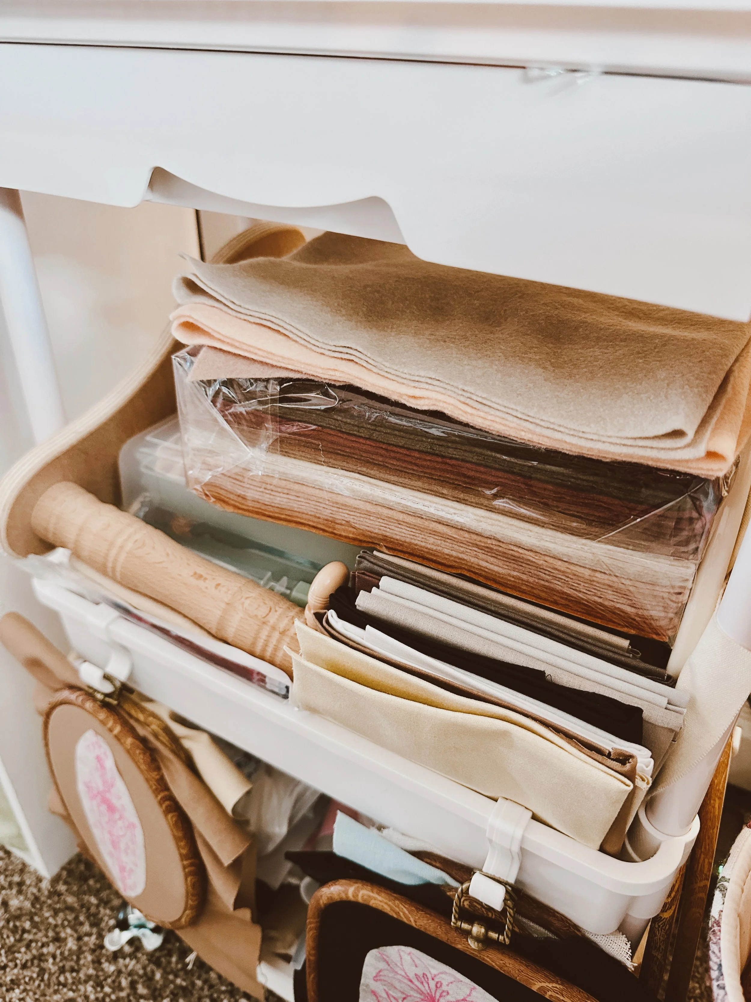 Close-up view of a storage cart filled with fabric, papers, and wrapped packages in neutral tones.
