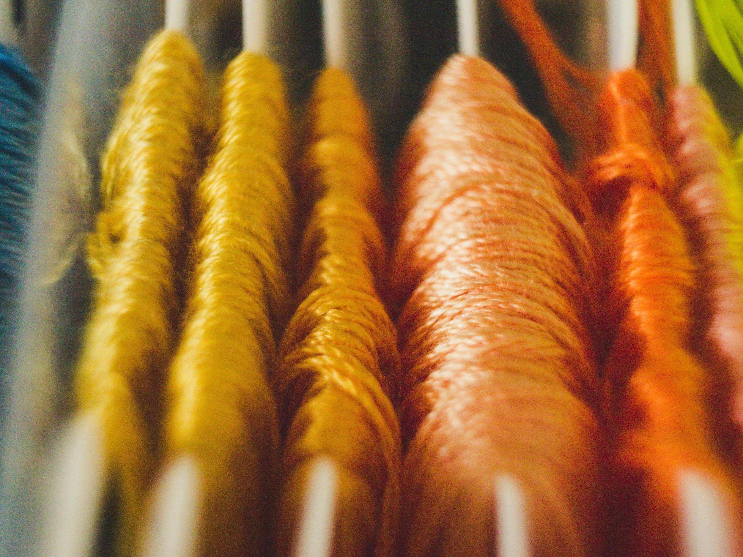 Close-up of multicolored yarn balls on a rack, including yellow, pink, orange, and green hues.