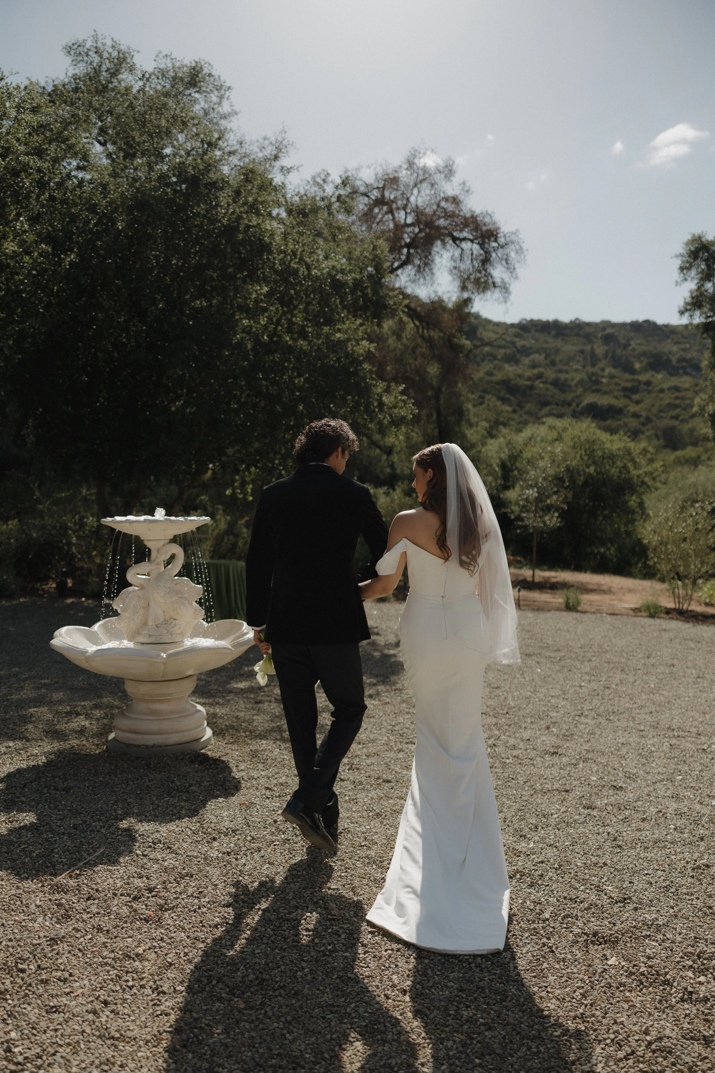 A couple walking towards a fountain during their wedding day 