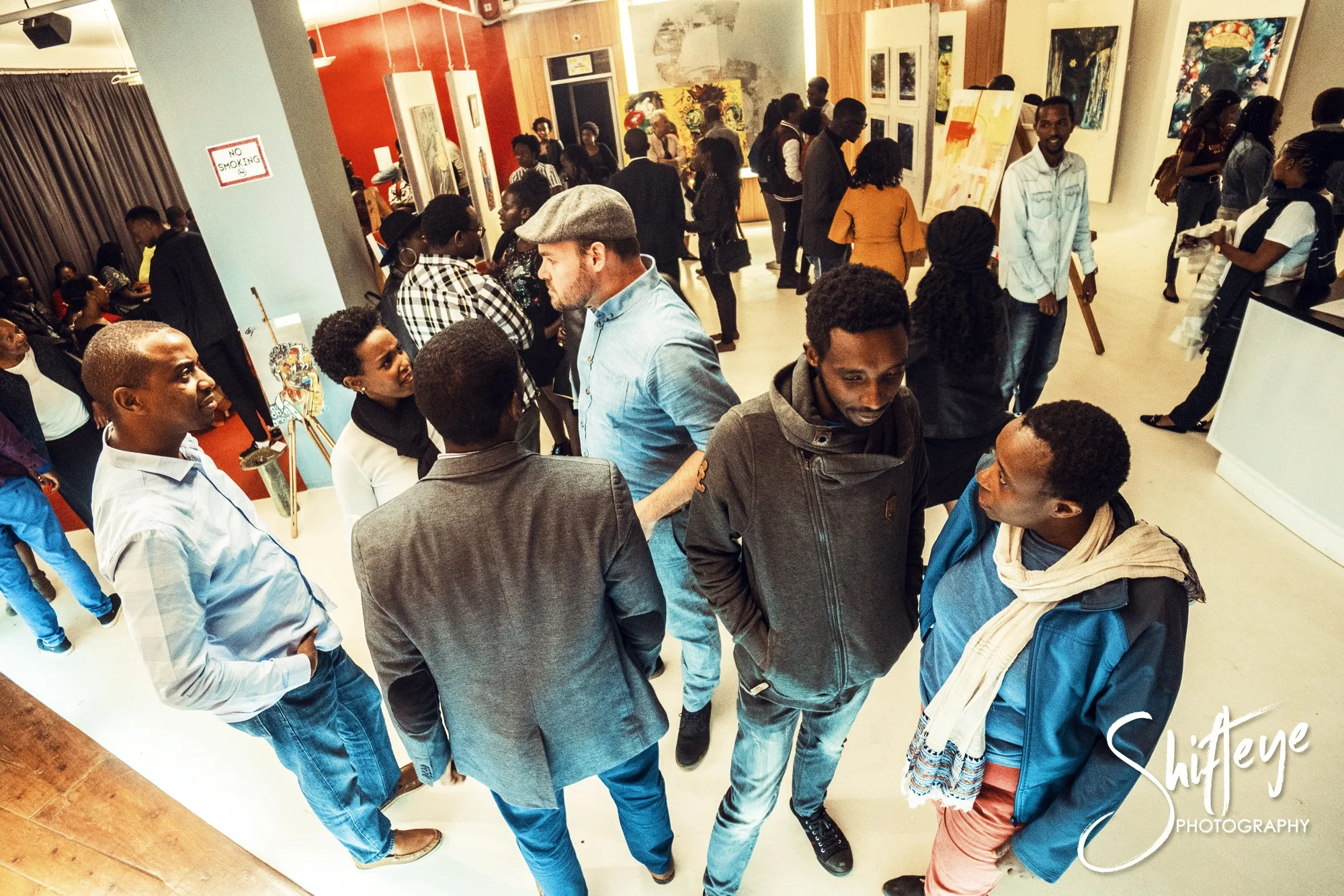 People attending an art gallery, observing and discussing various artworks displayed on the walls.
