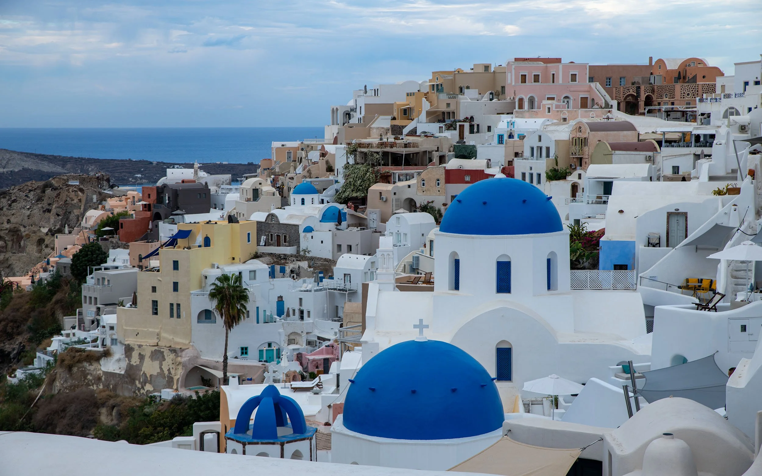 View of Santorini's white buildings with blue domes, overlooking the sea.