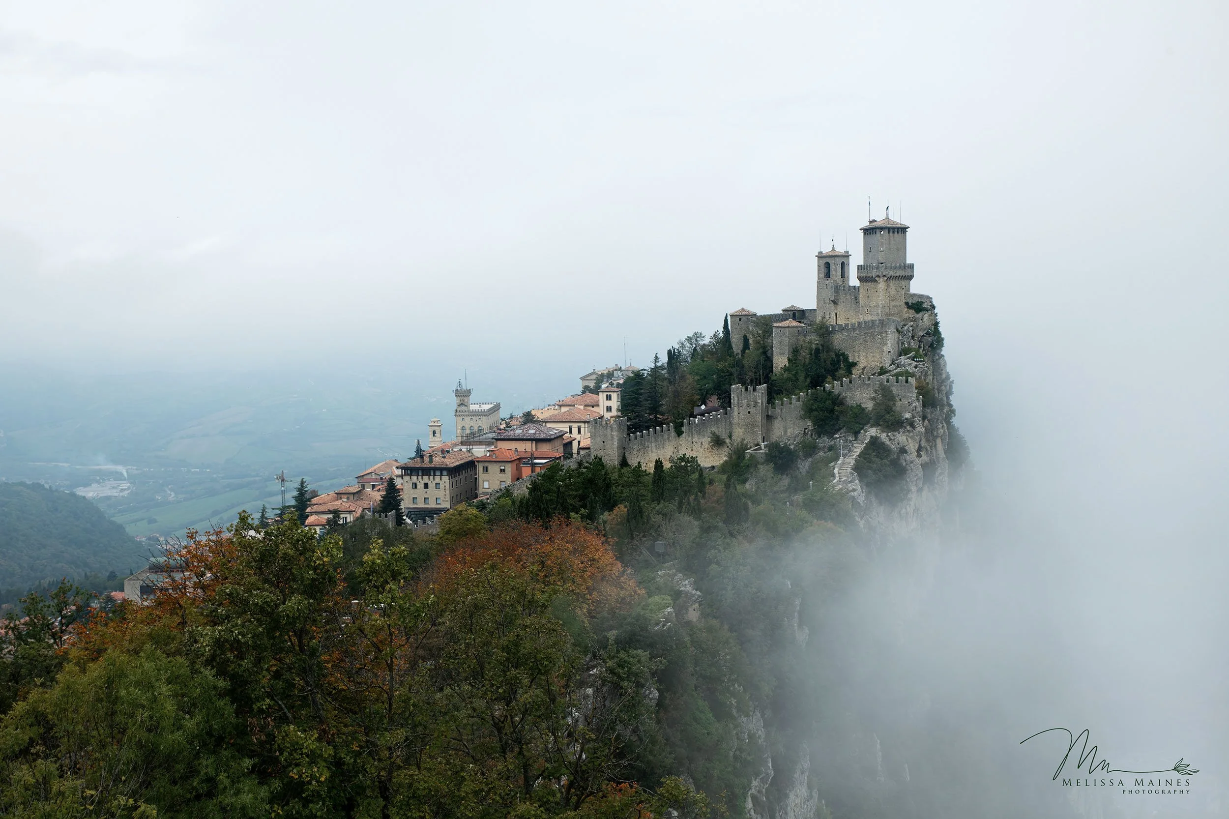 Tower of San Marino on a misty hilltop surrounded by foggy clouds.
