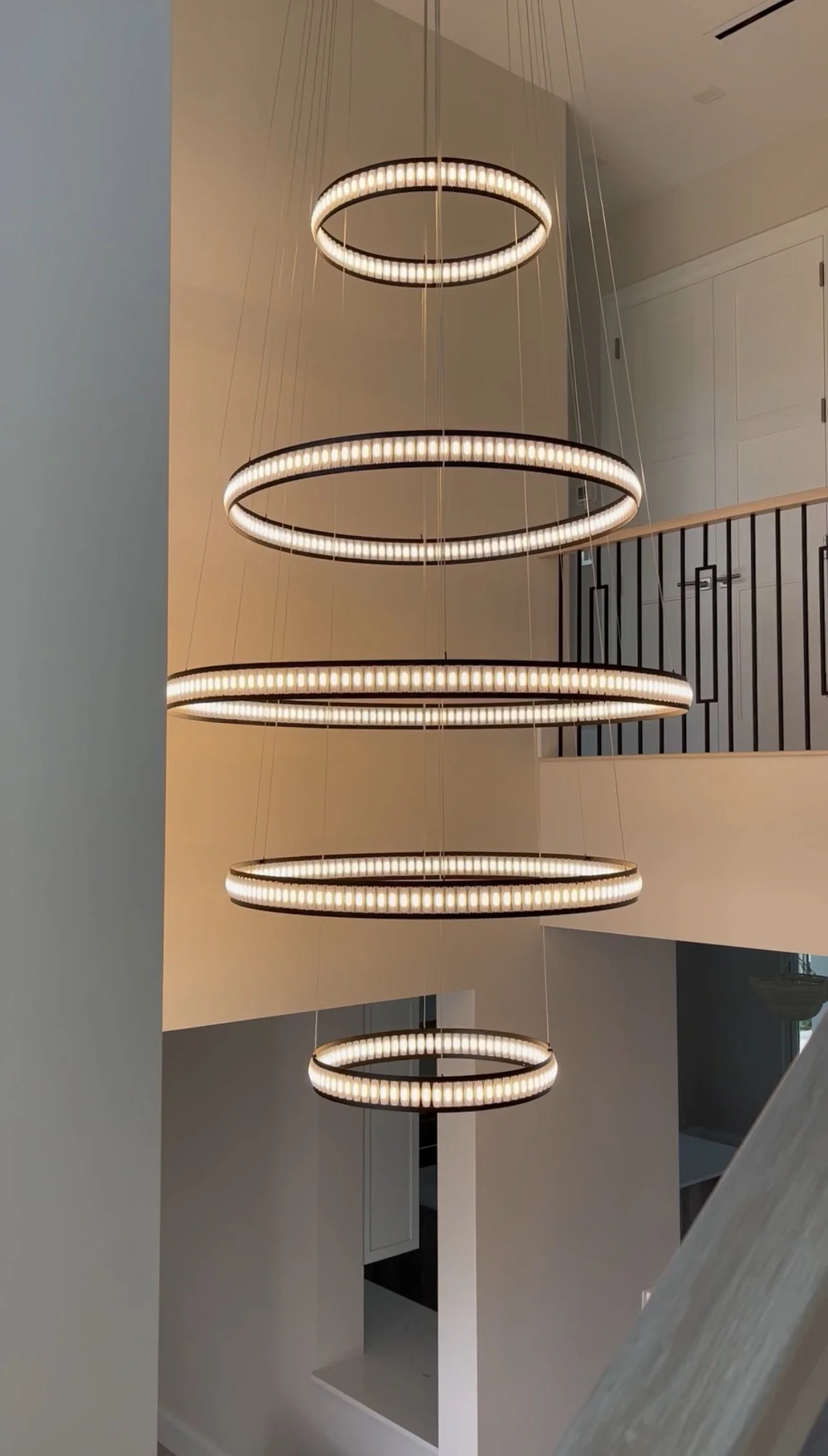 Modern multi-tiered circular chandelier with LED lights hanging in a contemporary home interior.