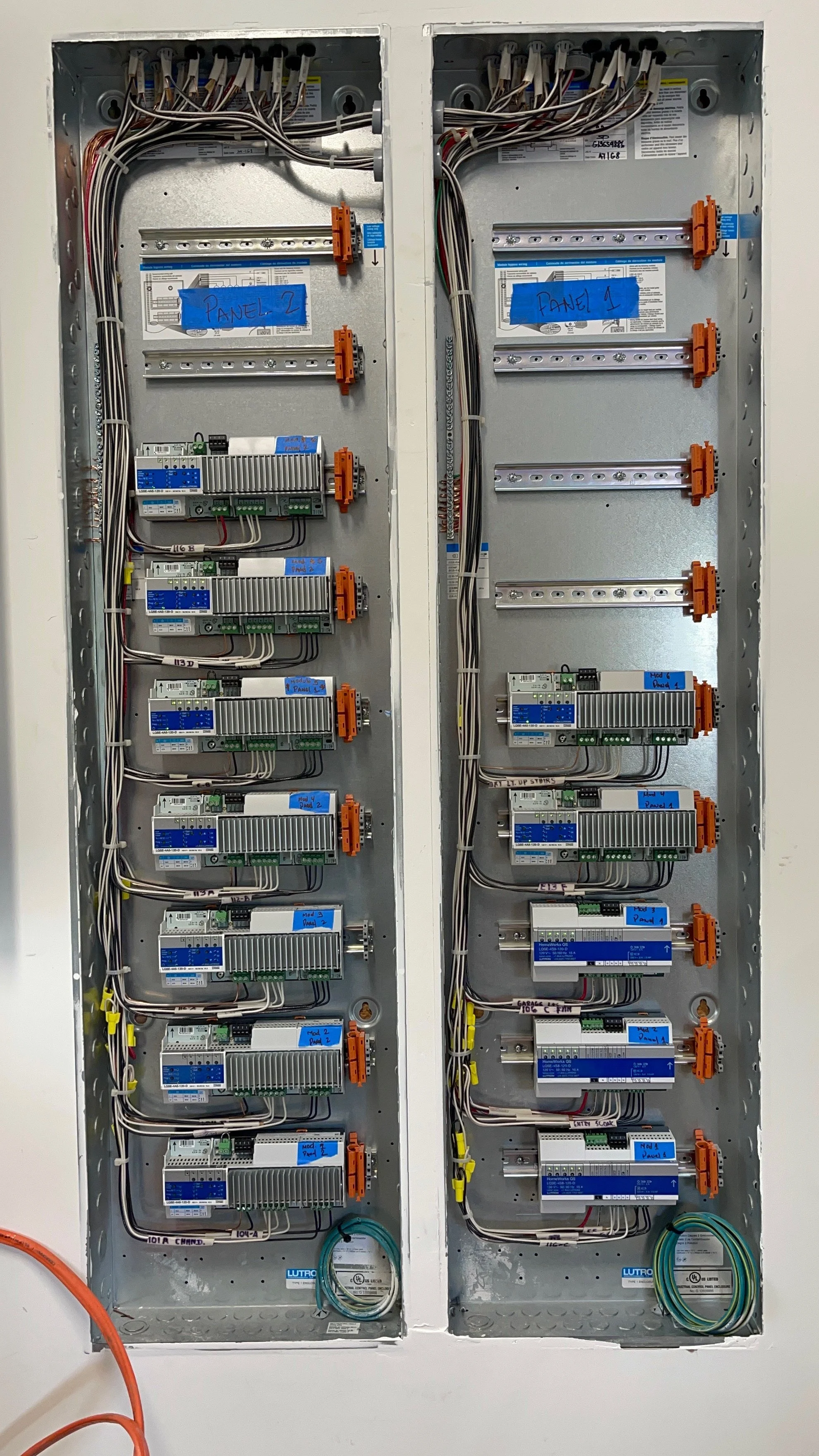 Electrical panel with multiple circuit breakers and wiring, labeled 'Panel 1' and 'Panel 2' on blue tape.