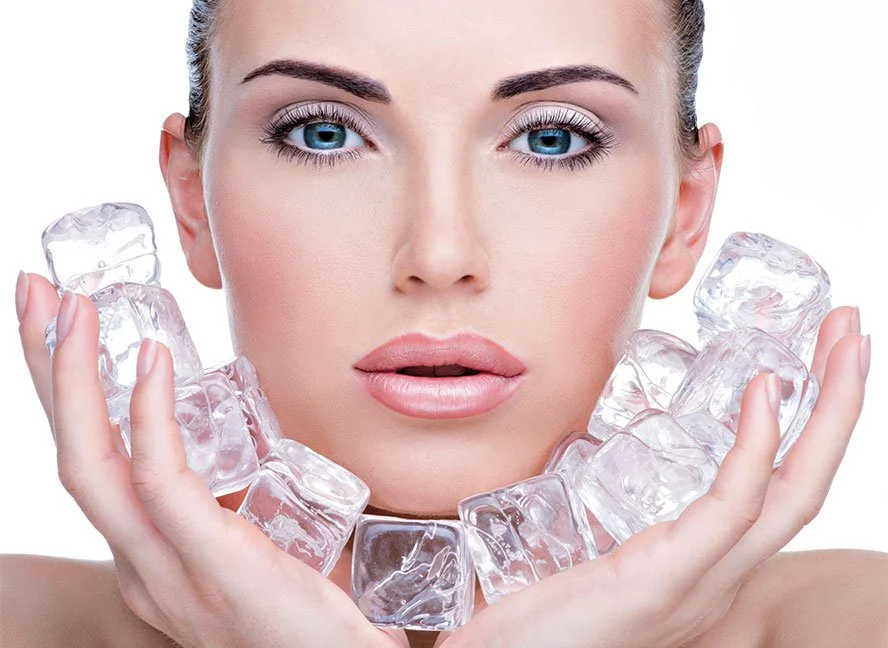 Nahaufnahme eines Models mit blauen Augen und voller Lippen, das Eiswürfel hält, um den Hals trägt und eine weiße Schmucknecklace.