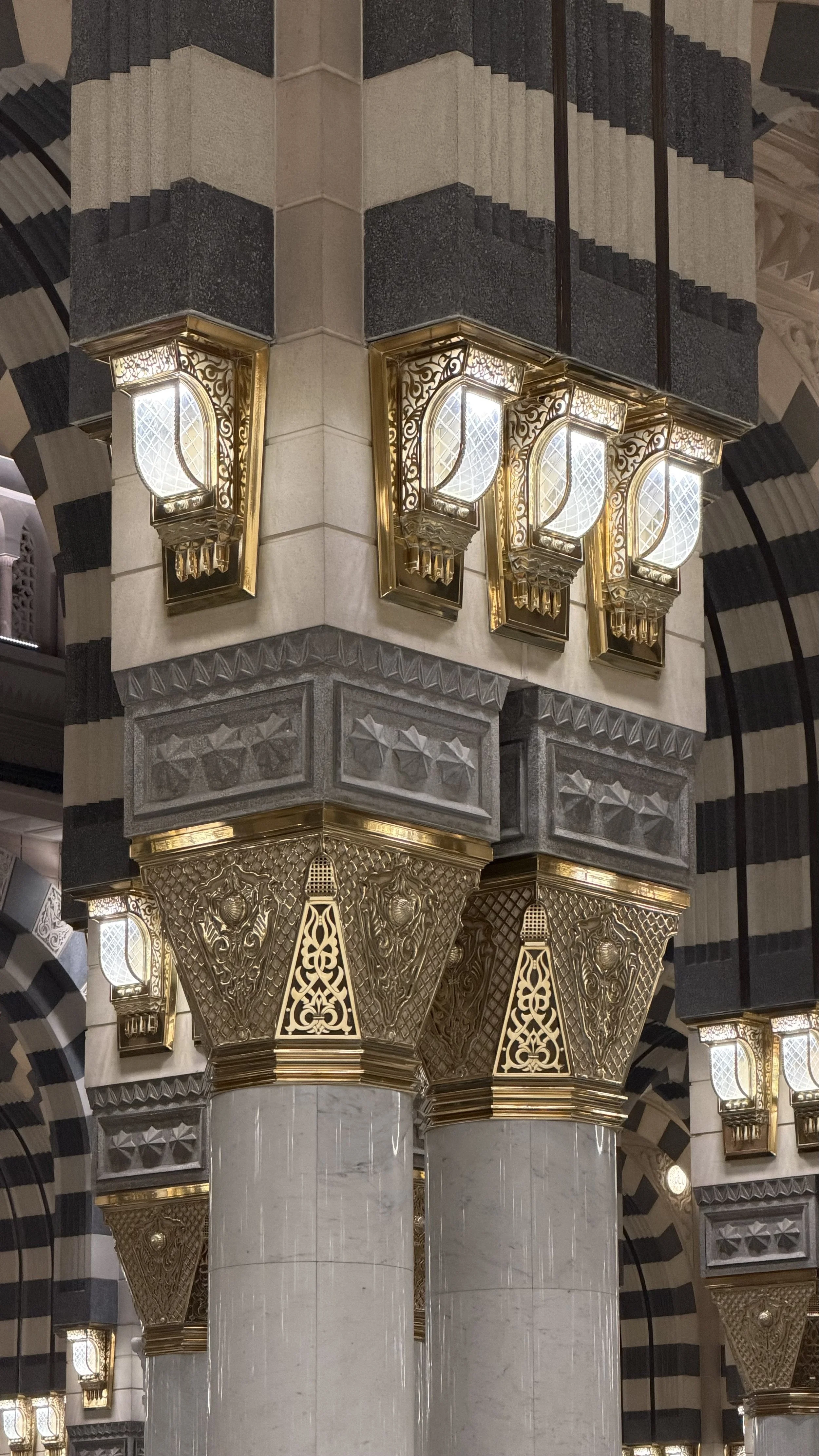 Colonnes ornées de décorations en or avec des appliques en verre, dans une architecture de style islamique ou mauresque.