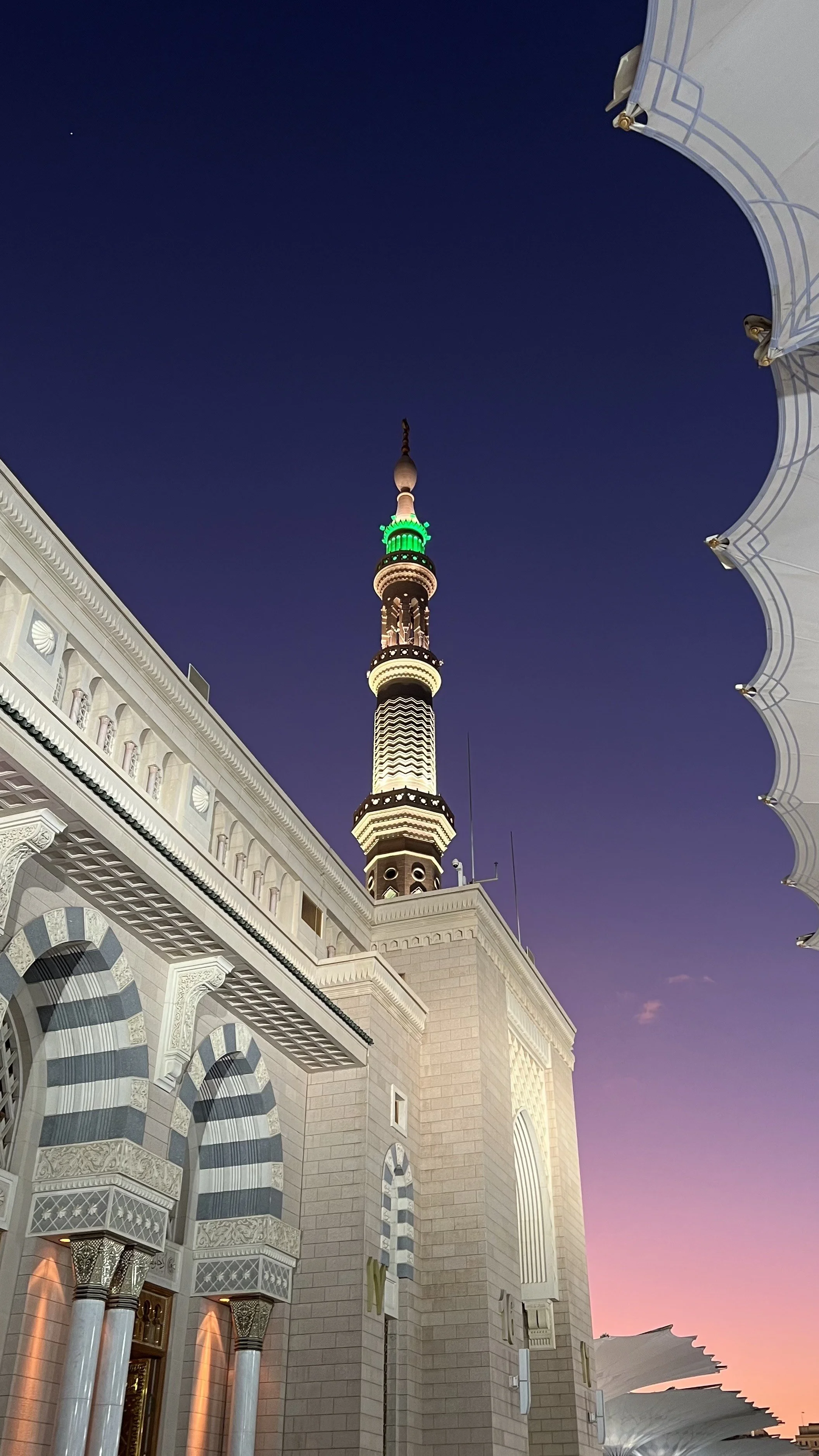 Photo de la Mosquée Hassan II avec sa tour illuminée, ciel crépusculaire avec étoiles, architecte avec arches en pierre et détails ornés.