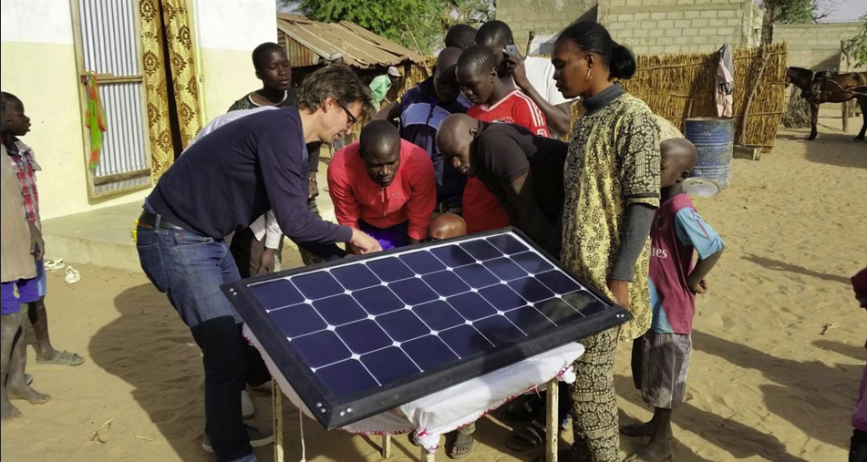 Group of people gathered around a solar panel, learning the nuances of solar energy