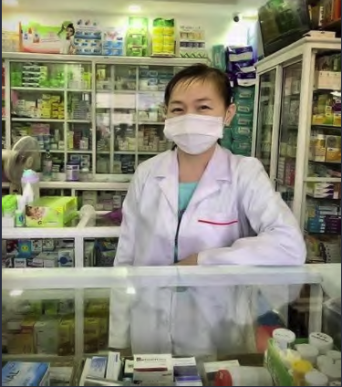 Woman wearing a white mask behind pharmacy desk in Cambodia