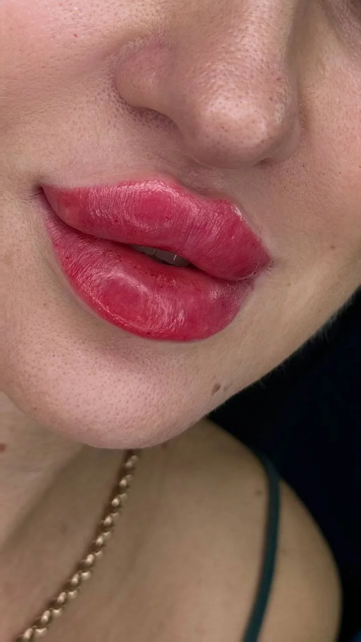 Close-up of a person's lips with lipstick, showing the nose and part of the face.