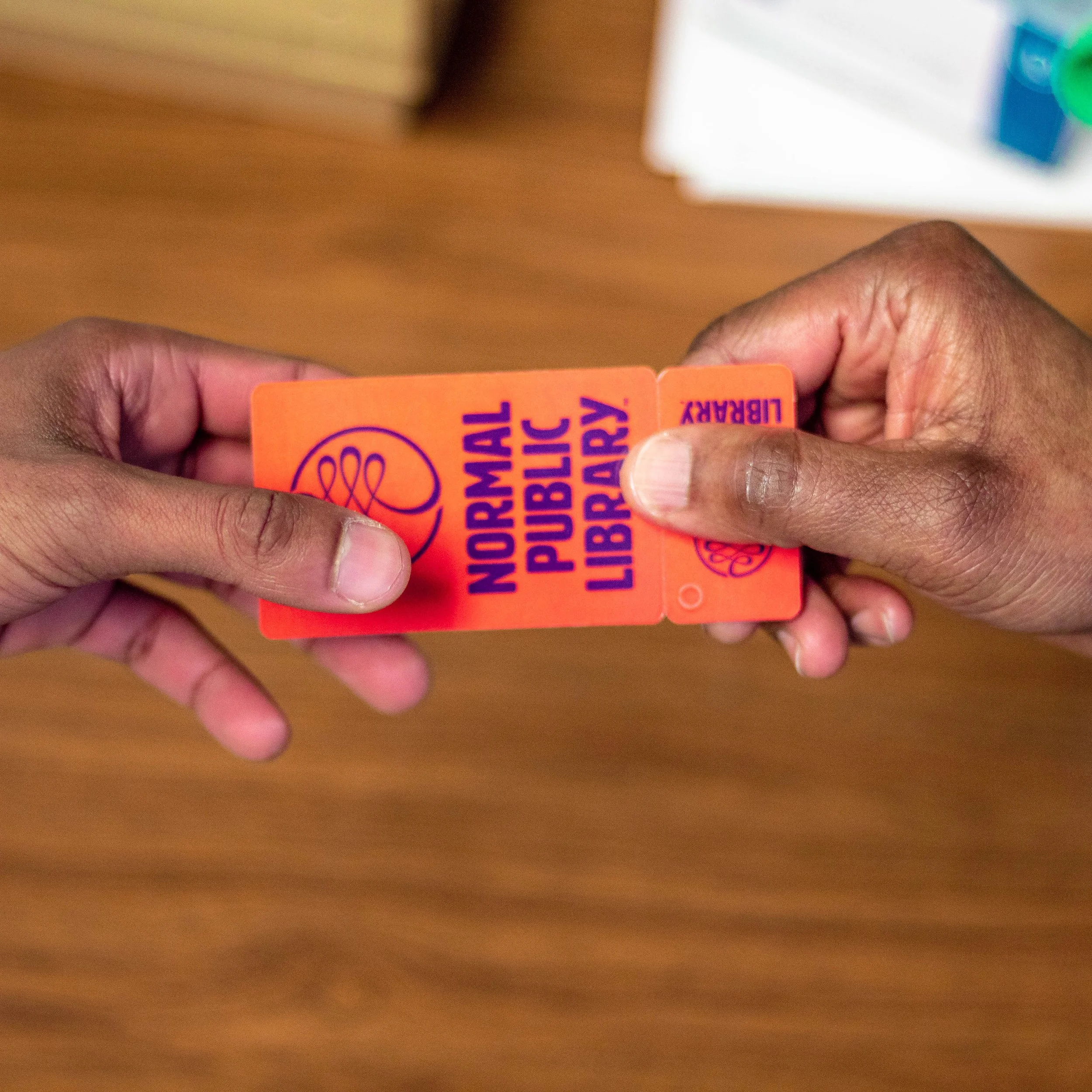 Two hands holding an orange library card