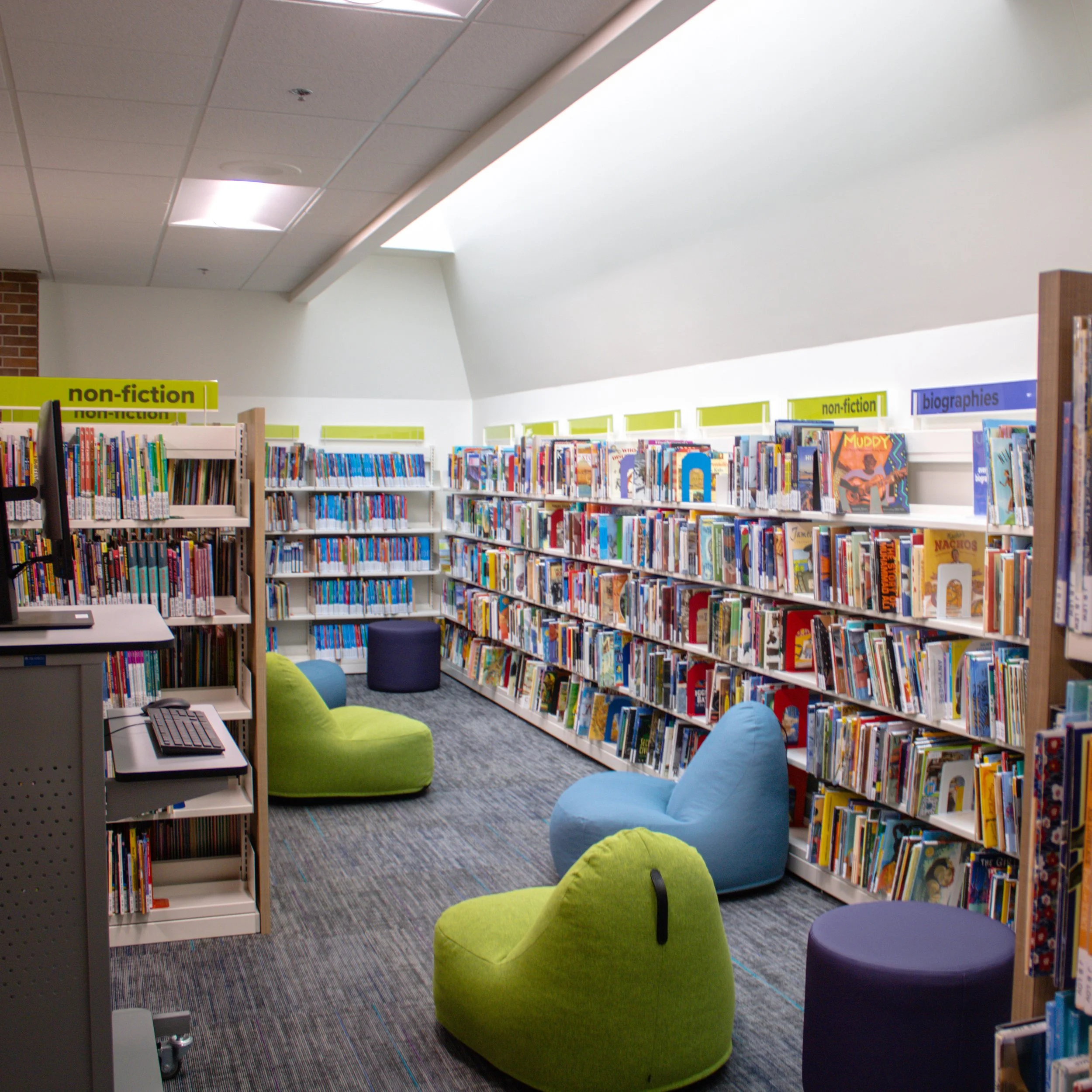 Corner of the library surrounded by bookshelves and floor cushions.