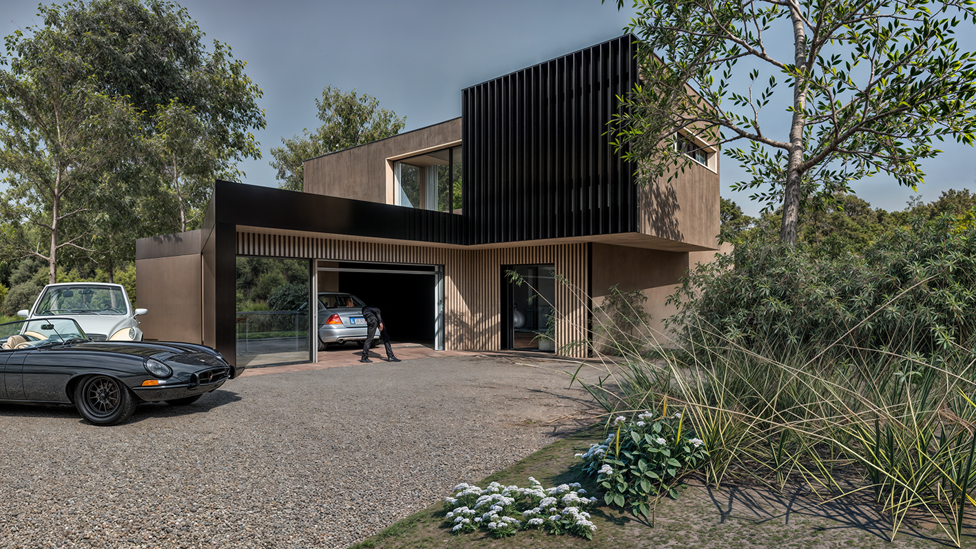 Maison moderne avec garage et voitures anciennes devant, entourée d'arbres et de végétation, en journée.