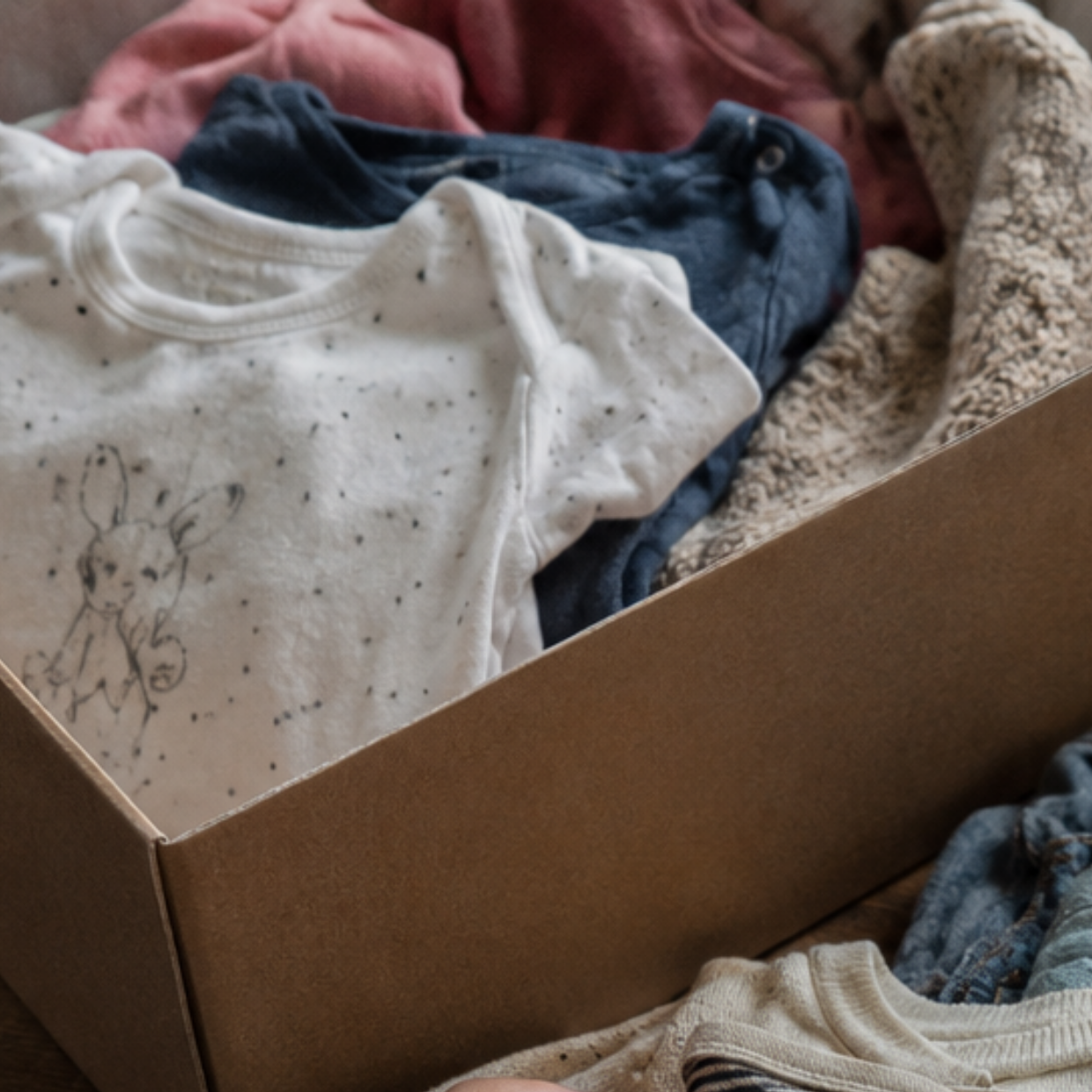 kartonnen doos met babykleertjes