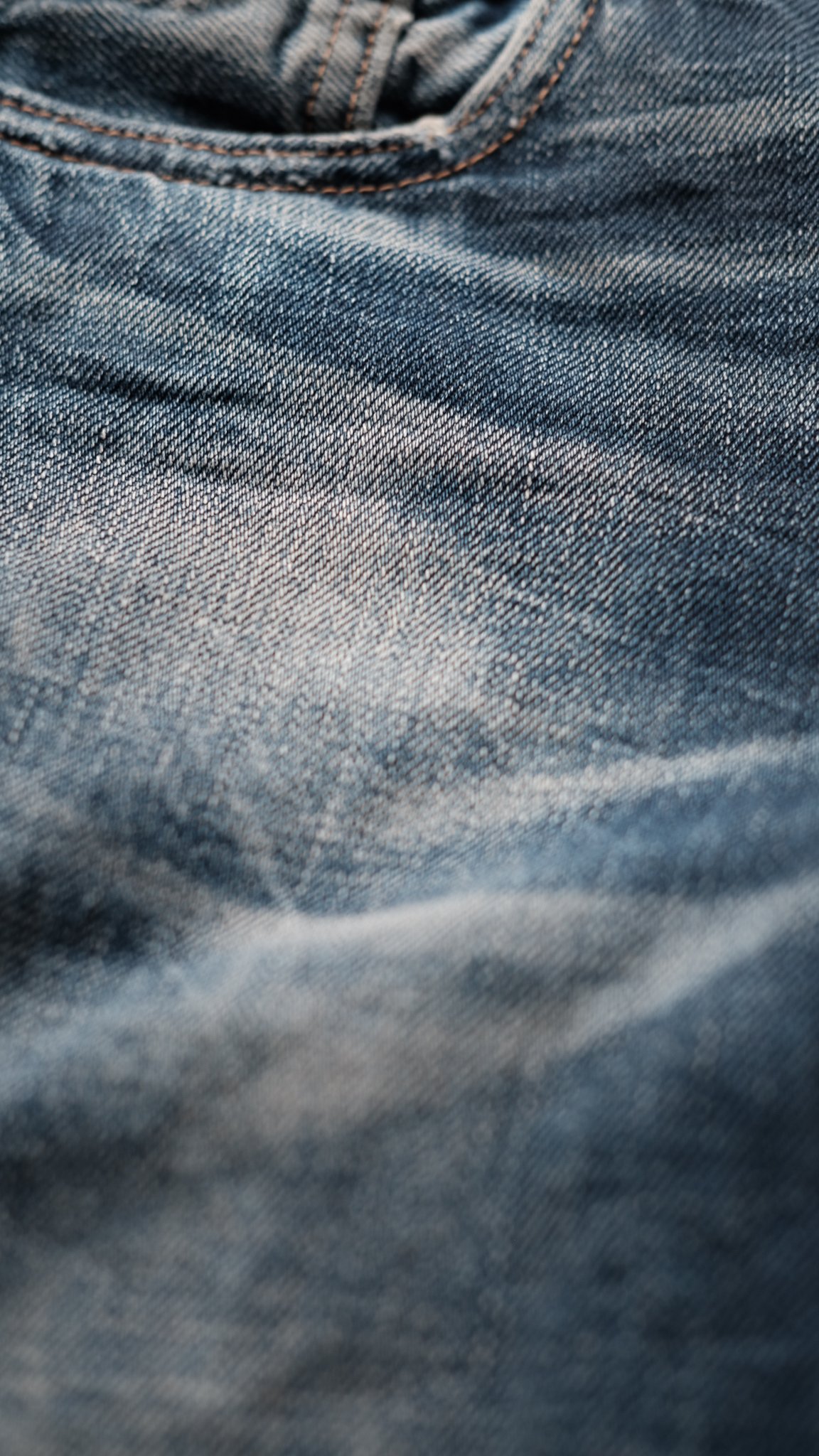 Close-up van blauwe denimstof, met zichtbare textuur en naden.