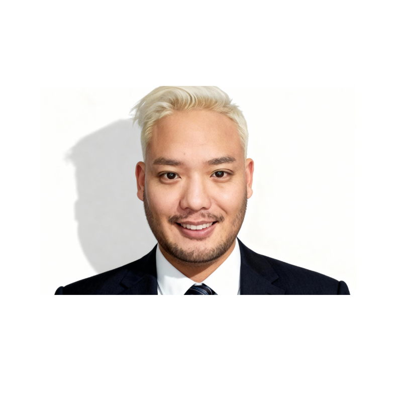 A man in a dark suit, white shirt, and tie smiling at the camera against a white background.