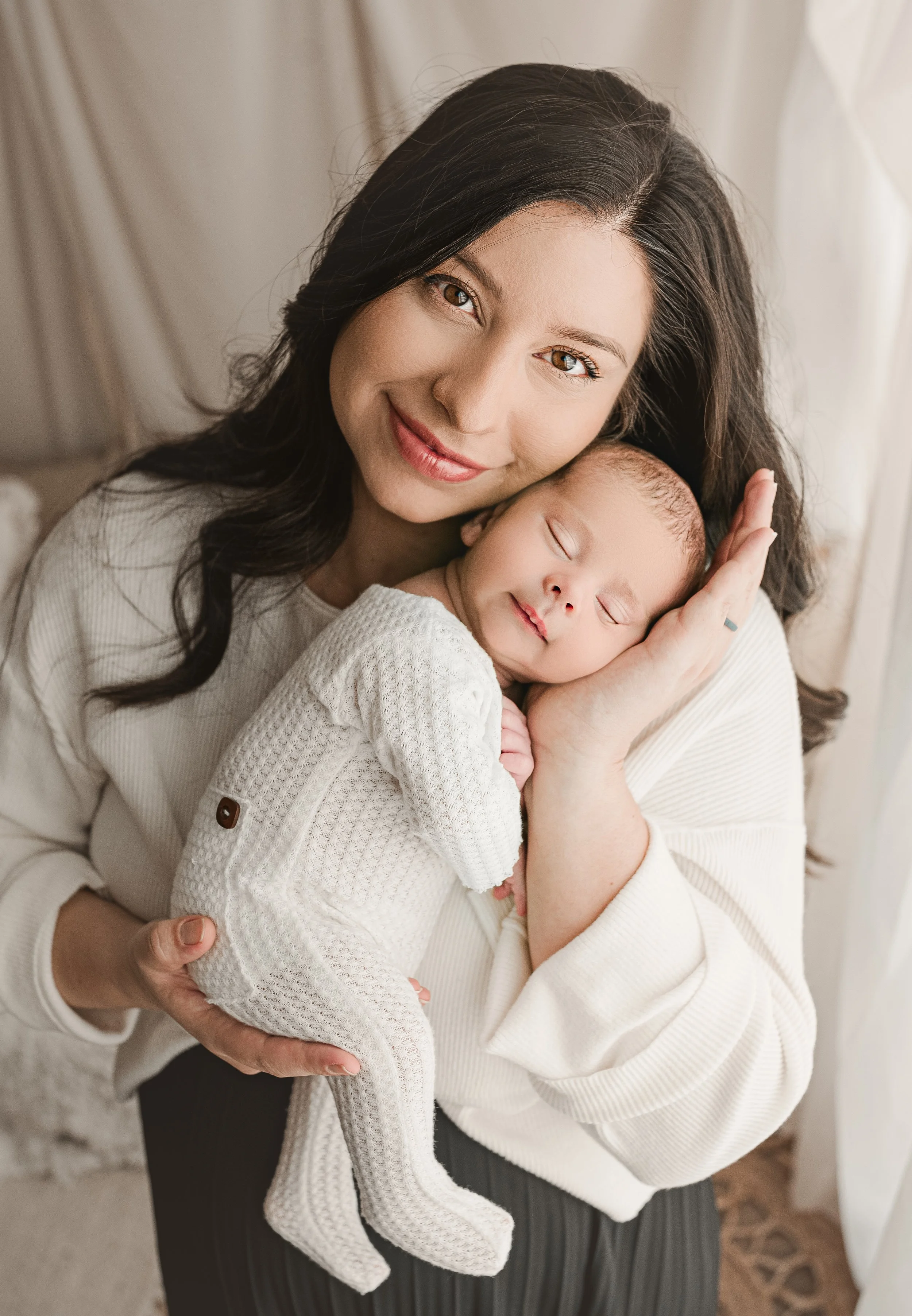 Bright lifestyle studio portrait of a mother holding her newborn baby