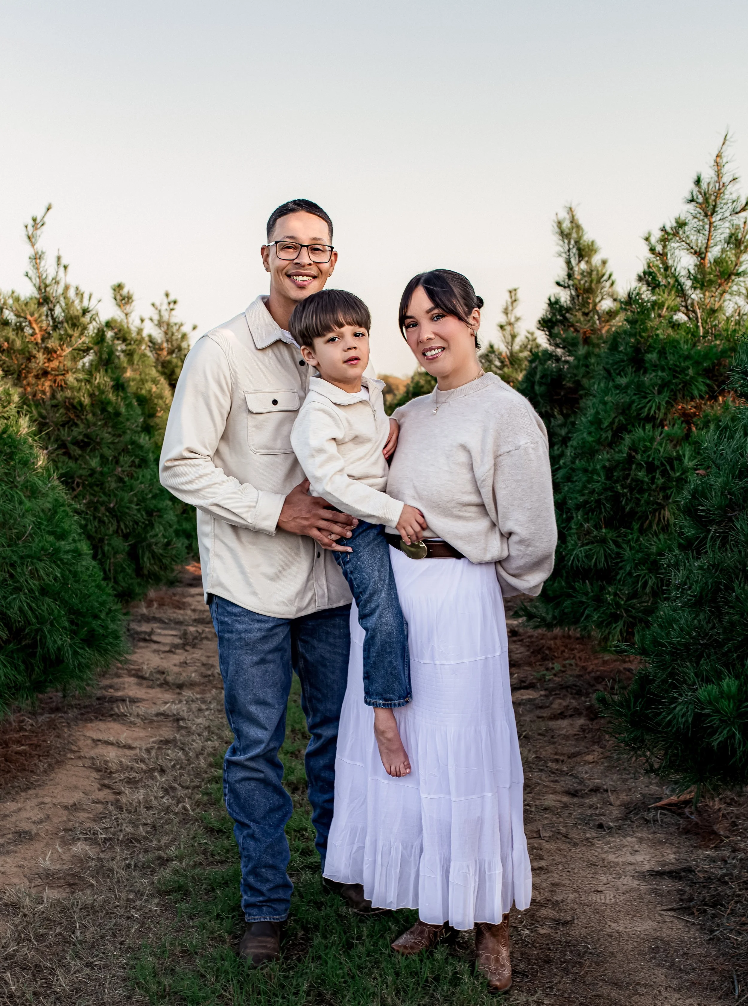 family of three posed and smiling for the outdoor photo session in Round Rock