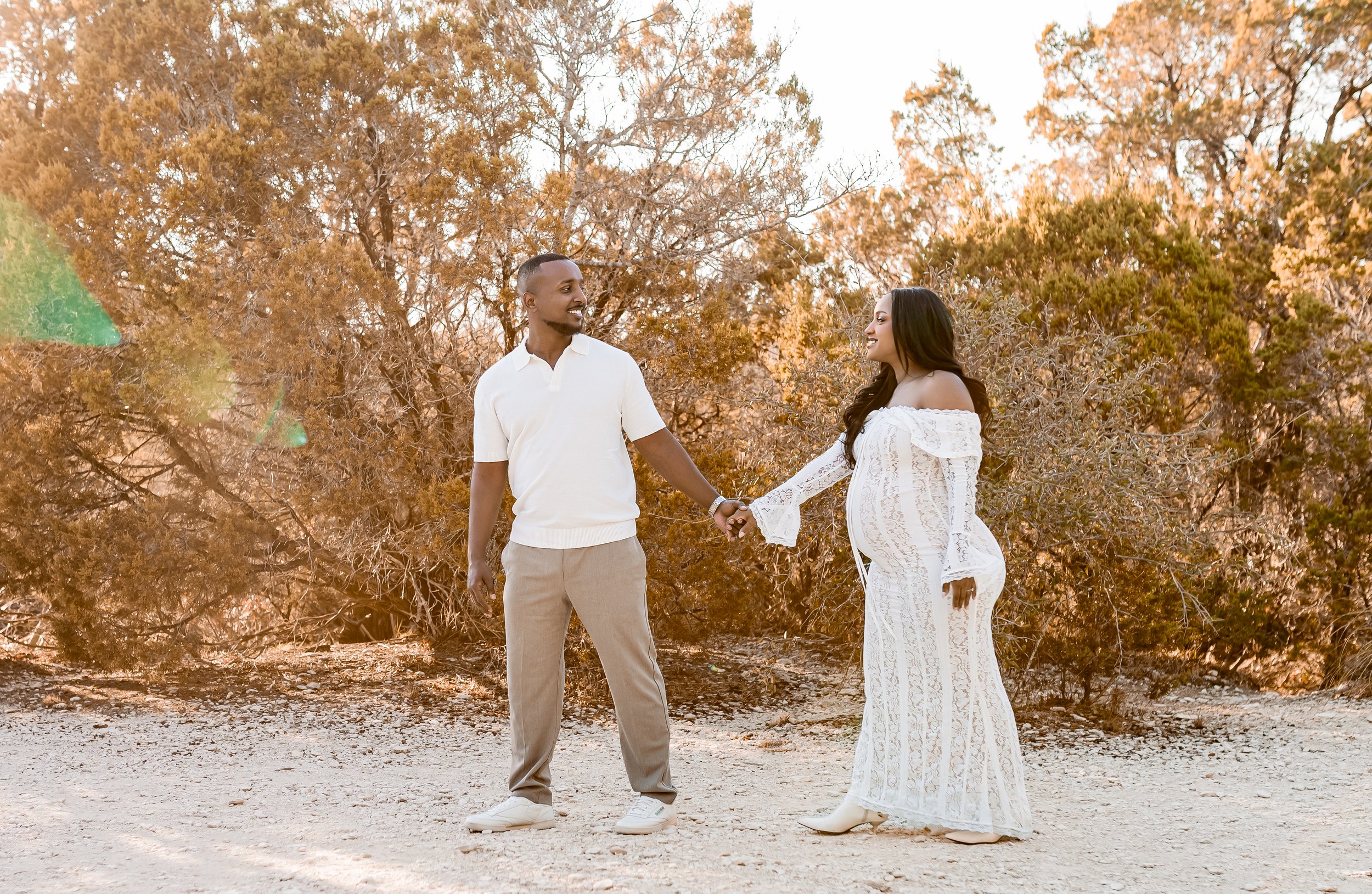 Expecting parents walking in a round rock park at golden hour