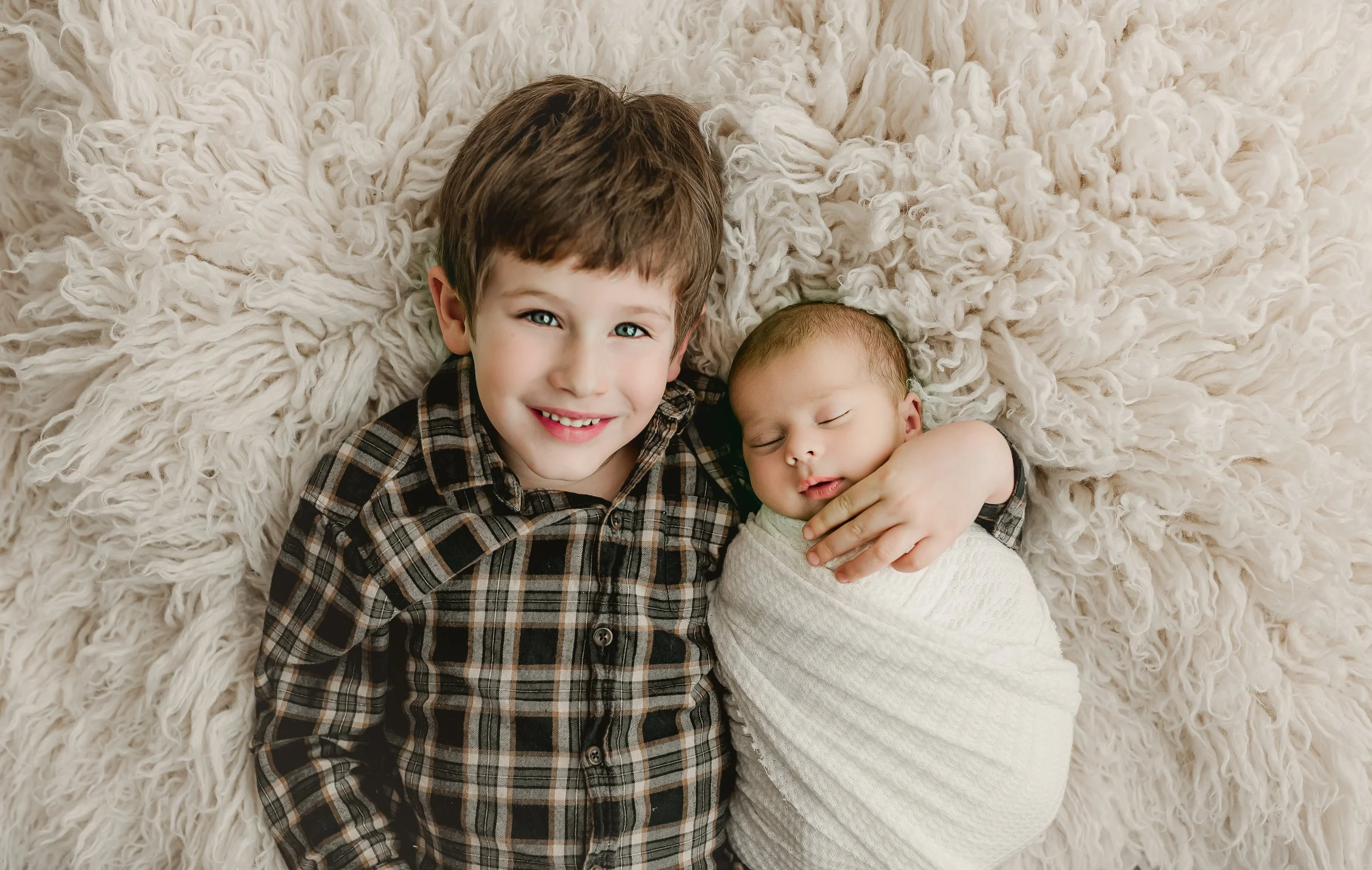 Sibling holding newborn baby during posed newborn photography in Round Rock