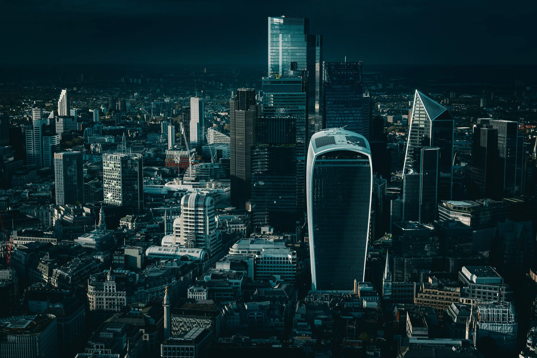 Aerial view of the modern London skyline at dusk with tall skyscrapers and historic buildings.