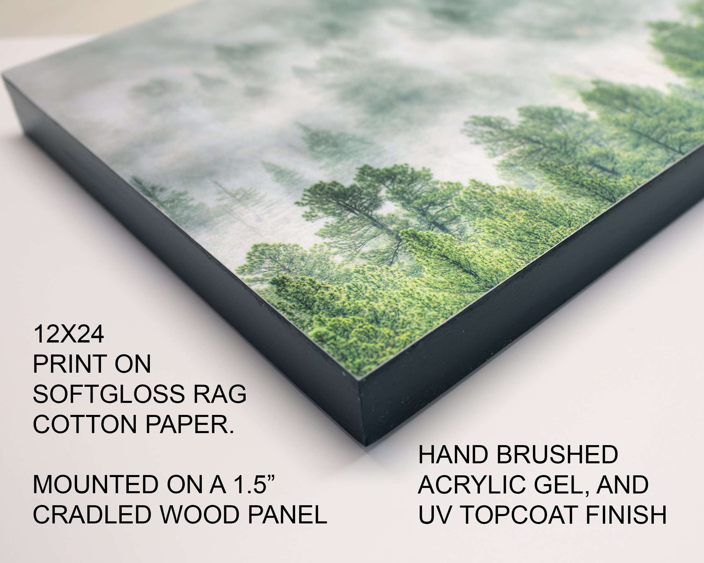 Close-up of a framed landscape print of trees and fog, mounted on a 1.5-inch cradled wood panel, with annotations describing it as a 12x24 print on softgloss rag cotton paper, hand brushed acrylic gel, and UV topcoat finish.