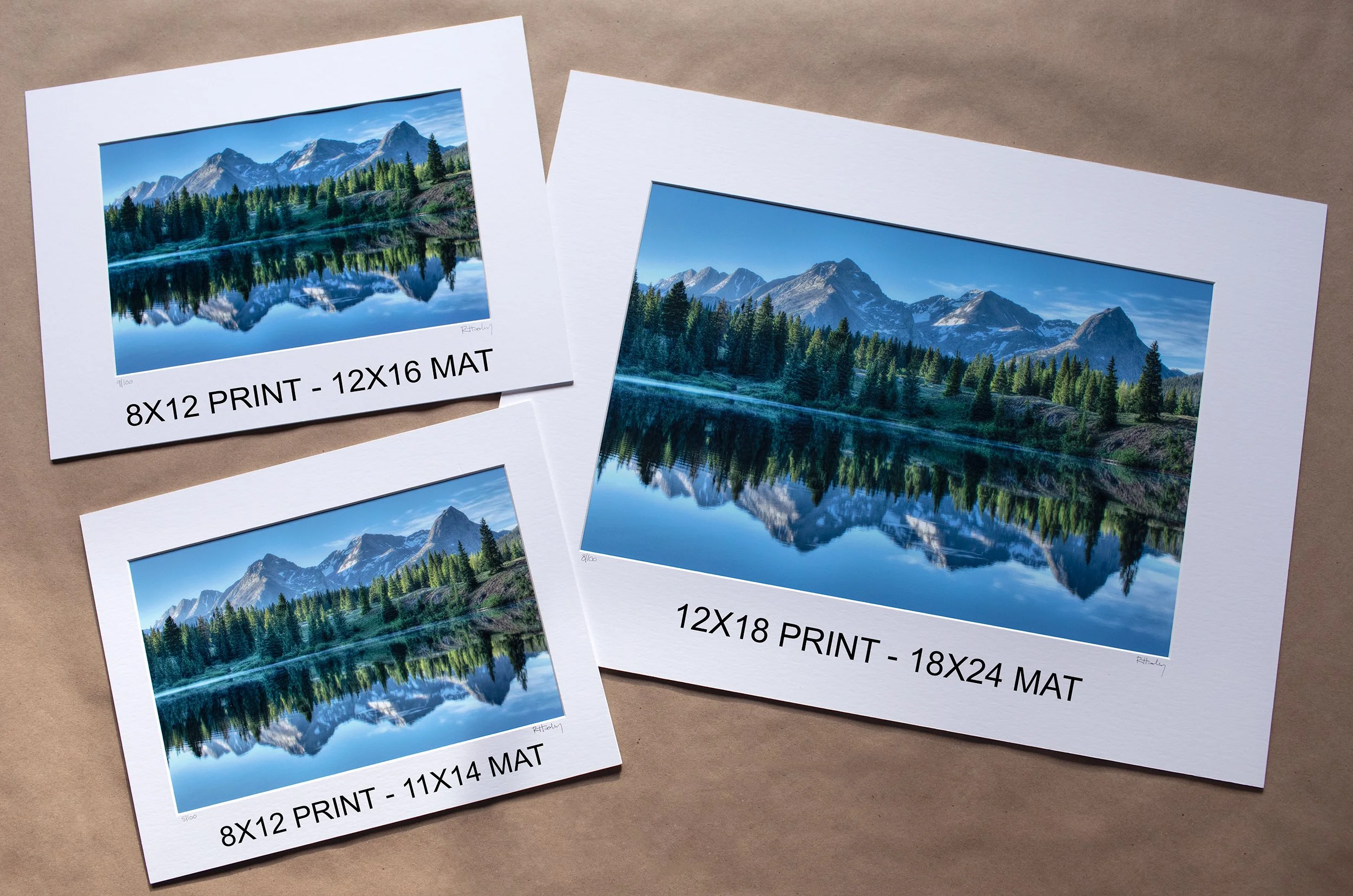 Three printed landscape photos of a mountain and forest scene, each labeled with different print sizes and paper types. One is an 8x12 print on 12x16 matte paper, the second is an 8x12 print on 11x14 matte paper, and the third is a 12x18 print on 18x24 matte paper.
