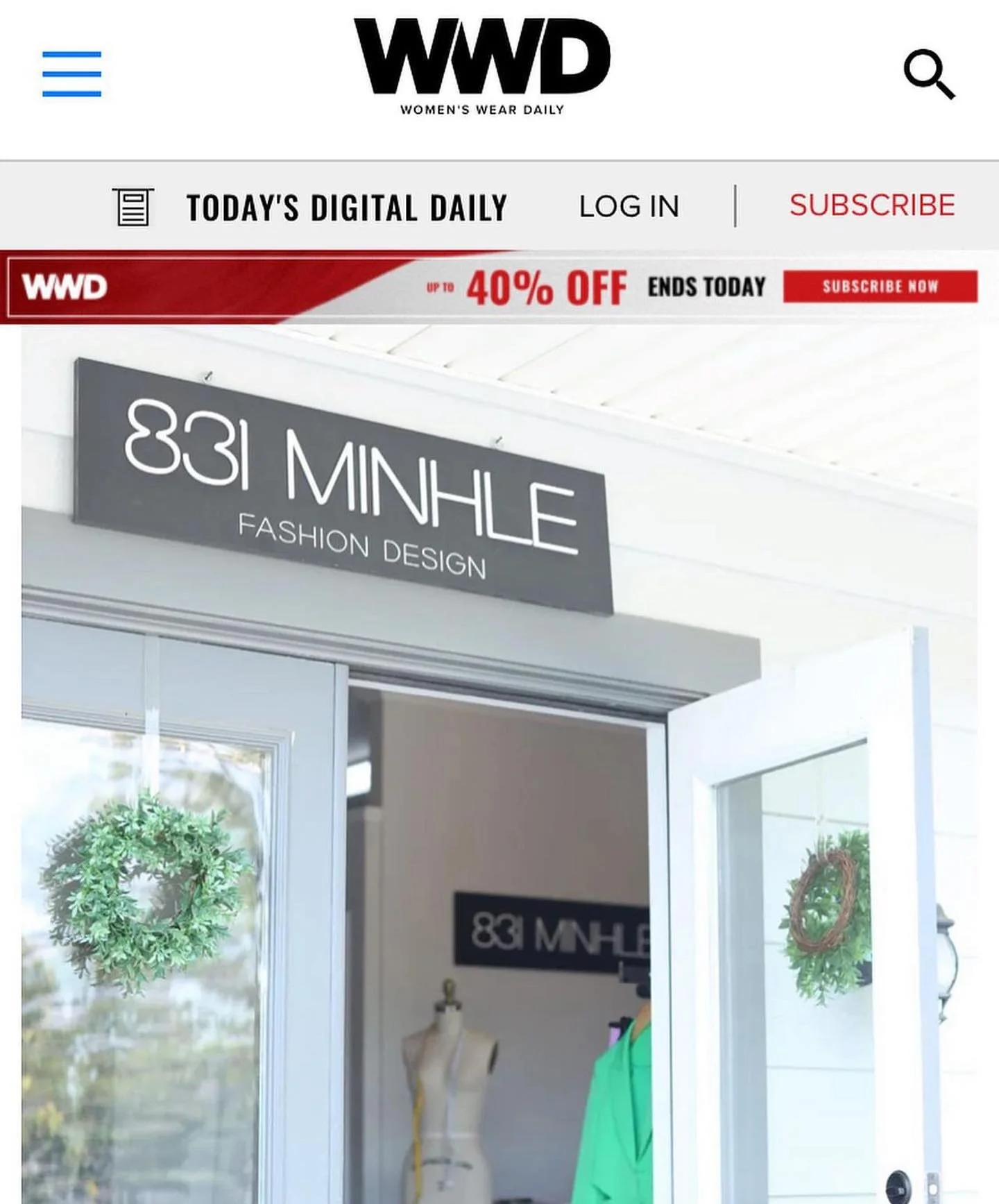 Entrance of a fashion design store with a sign that reads '831 MINHLE FASHION DESIGN' above the door. There is a wreath decoration on the glass door, and mannequins displayed inside.