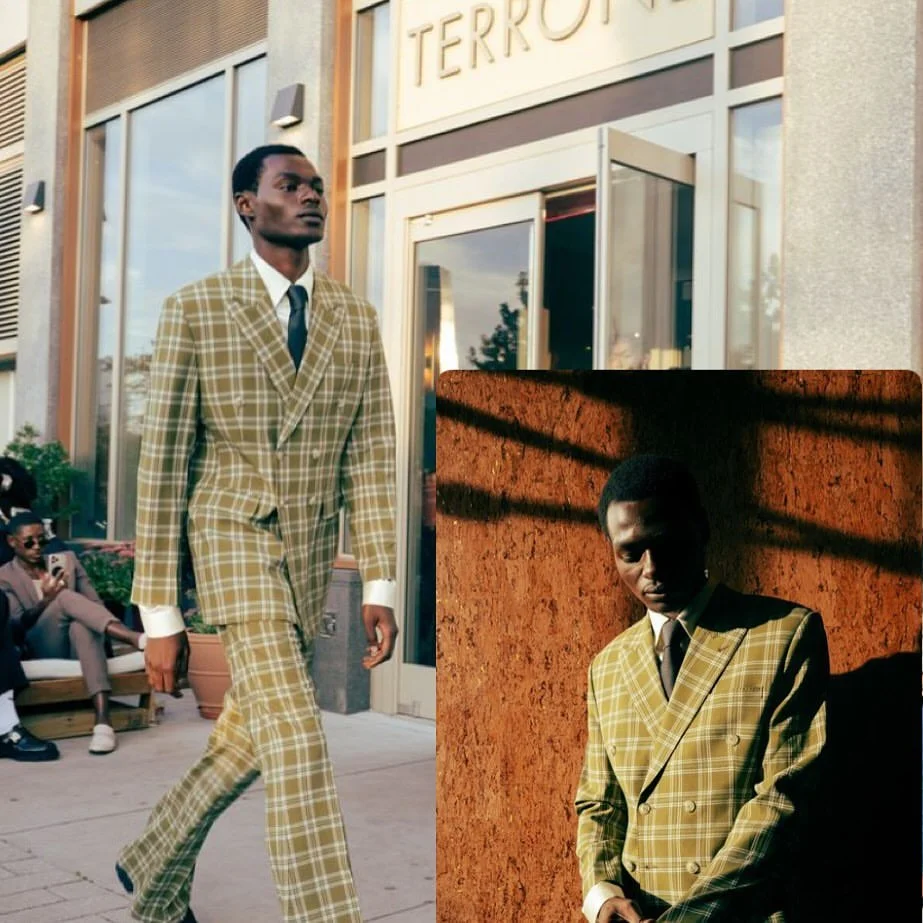 A man walking outside a building with a sign that reads 'TERROR,' wearing a plaid yellow suit and tie, with other people sitting nearby. In a smaller inset, the same man stands against a red brick wall, shadows cast across his face.