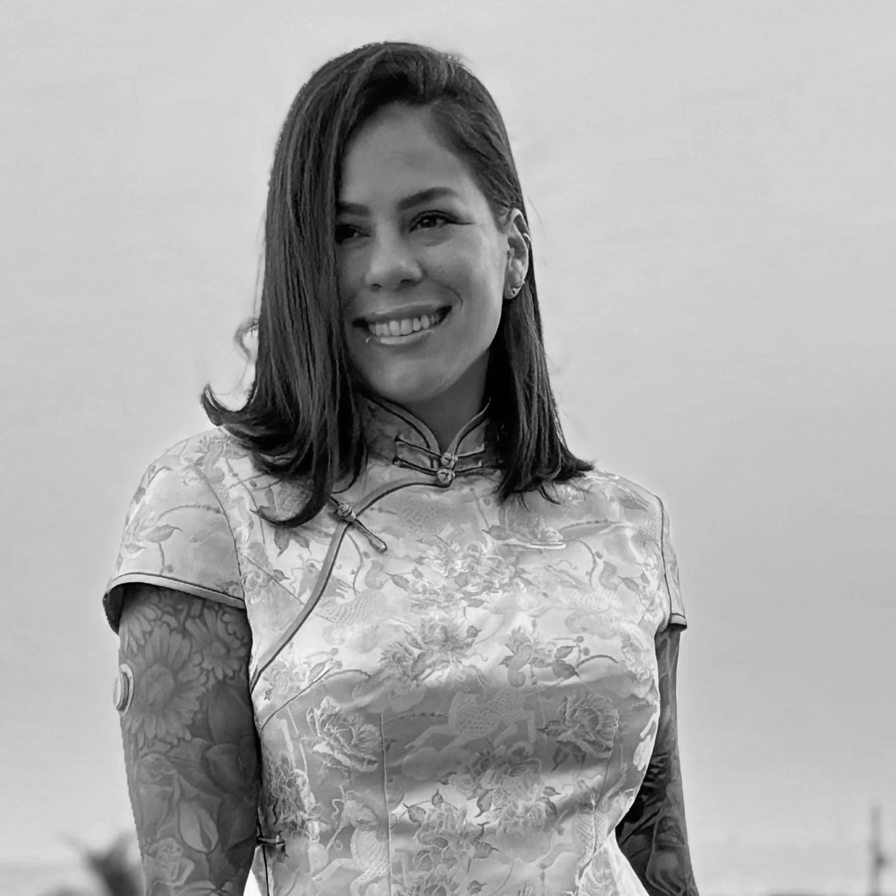 A woman with shoulder-length hair, wearing a traditional Chinese dress with a floral pattern, standing against a plain background.
