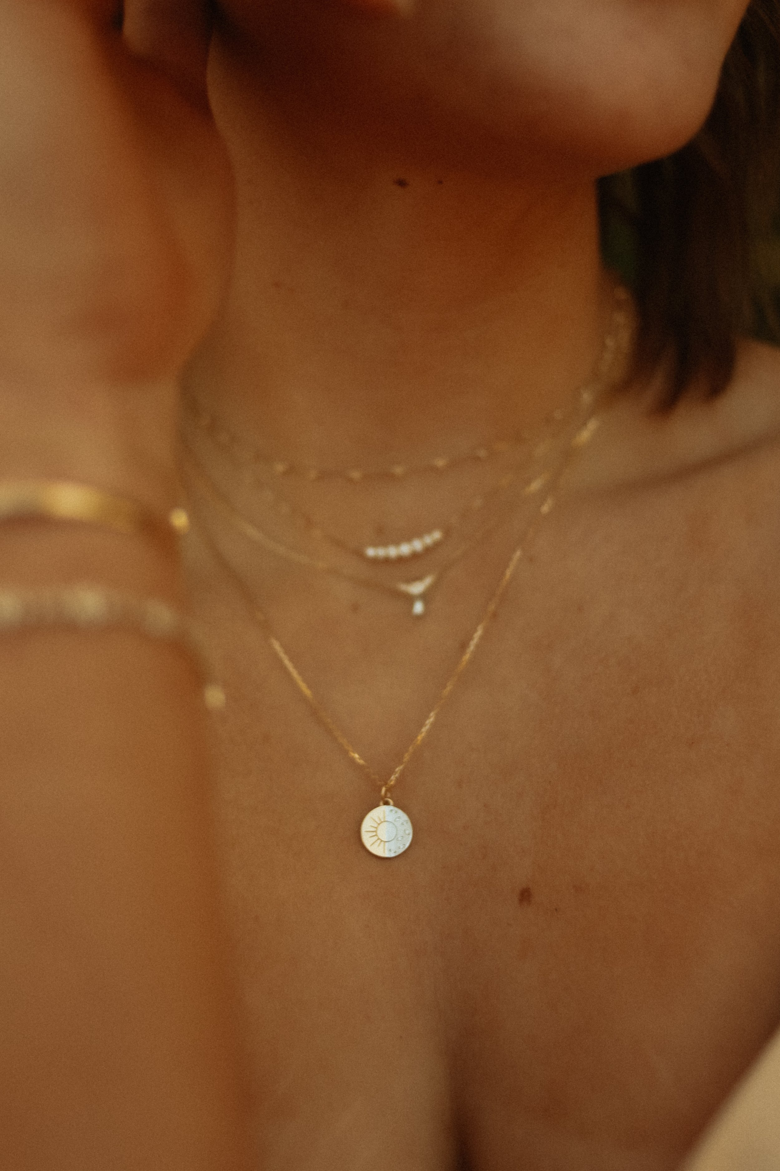 Close-up of a woman's neck and chest area wearing layered fine jewelry, in Deer Valley / Park City, Utah.