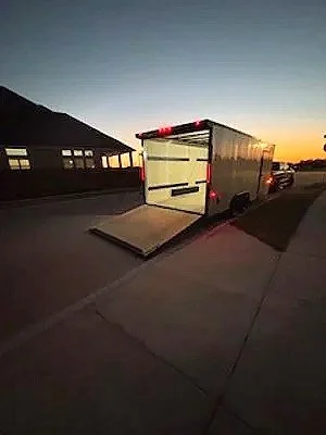 A trailer with a closed rear door parked on a driveway at sunset.