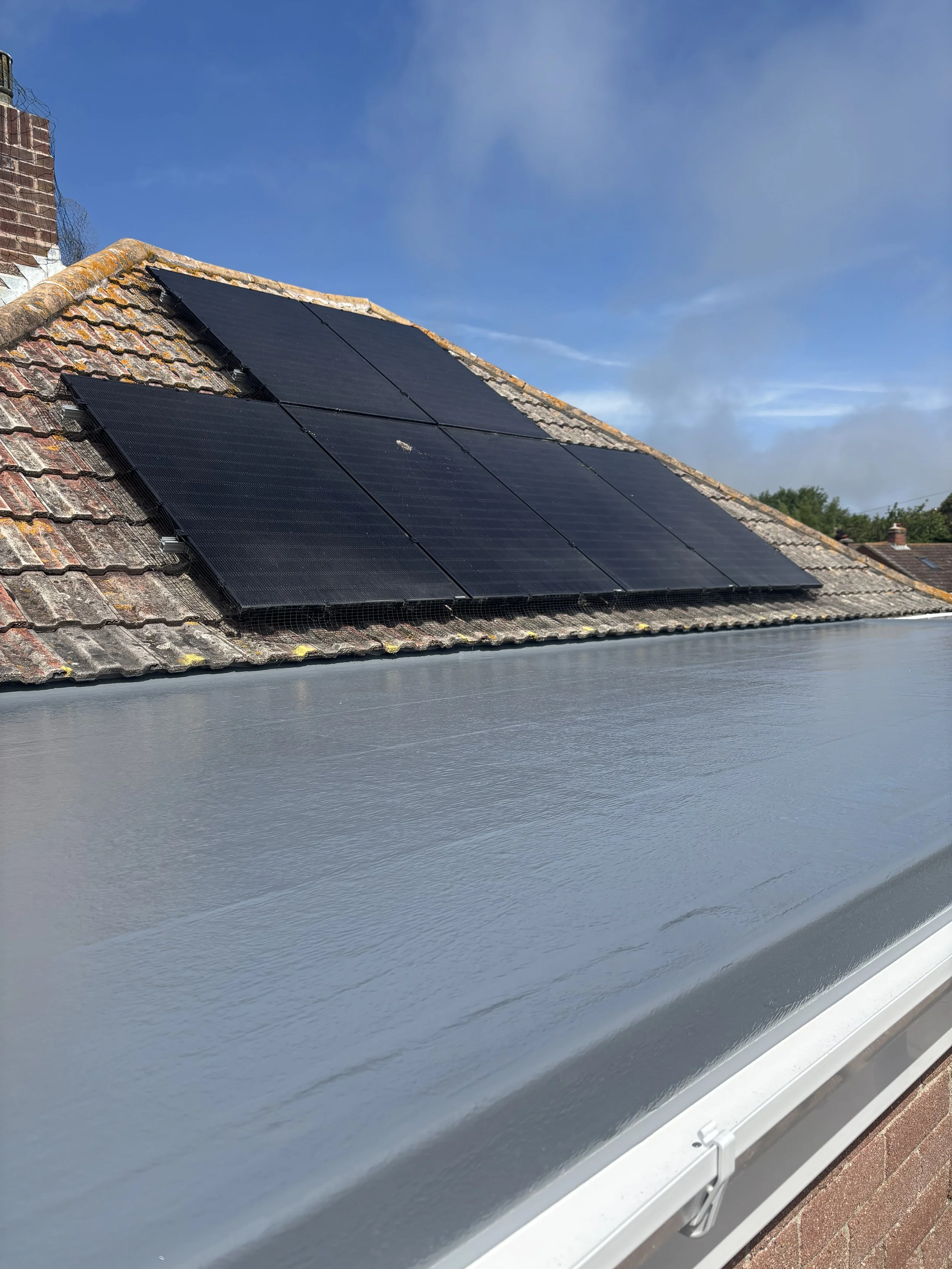 Solar panels installed on a house roof with a metal extension in the foreground.