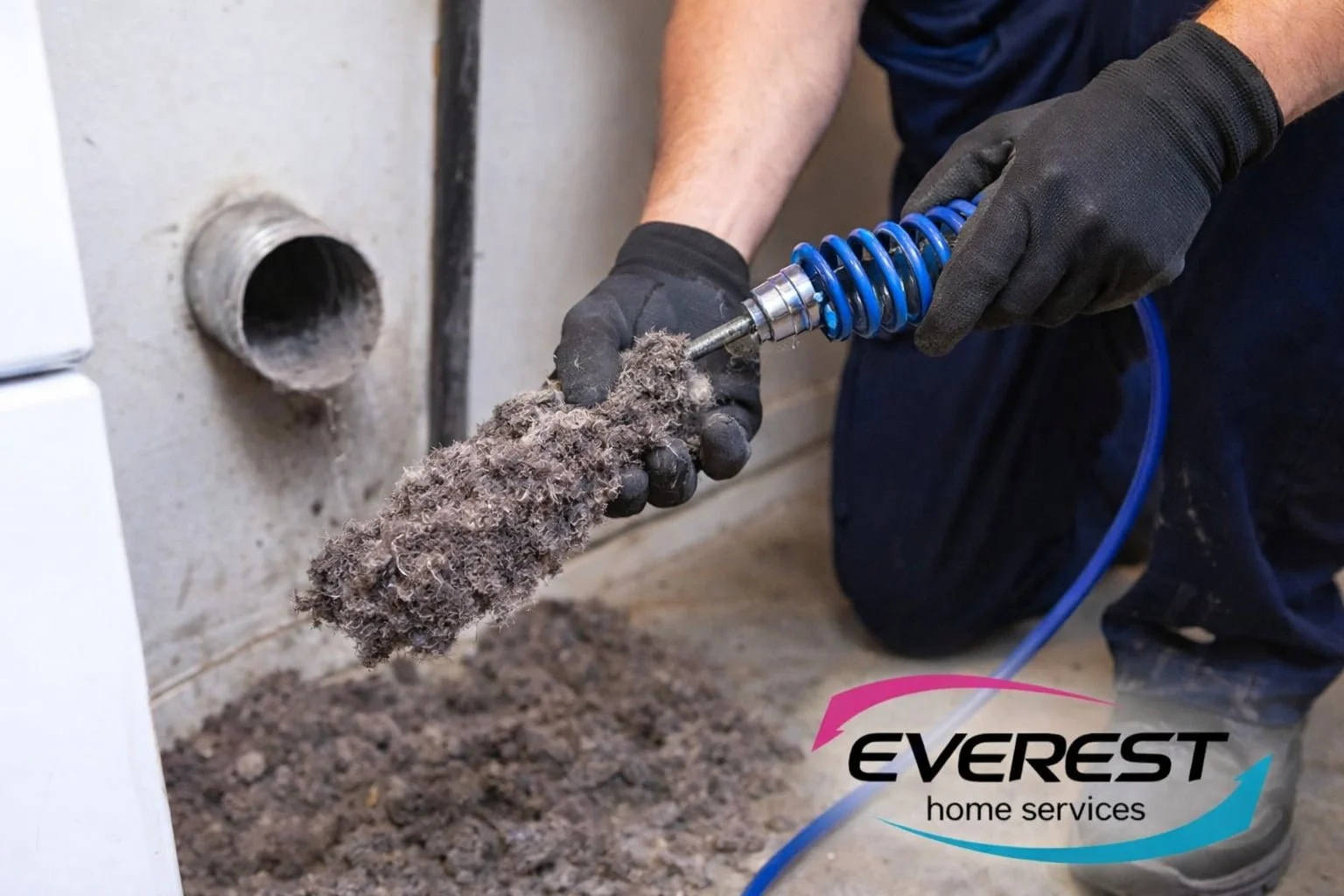 Technician removing heavy lint clog from dryer vent using professional cleaning equipment