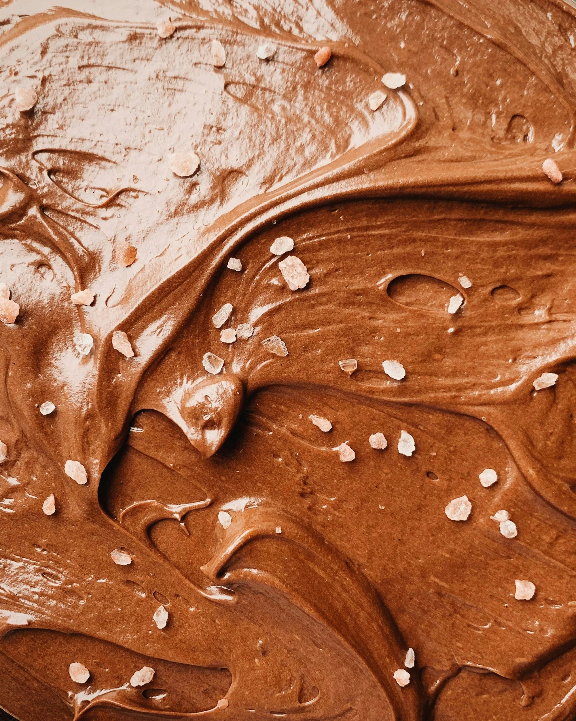 Close-up view of swirled chocolate frosting with a sprinkling of coarse salt.